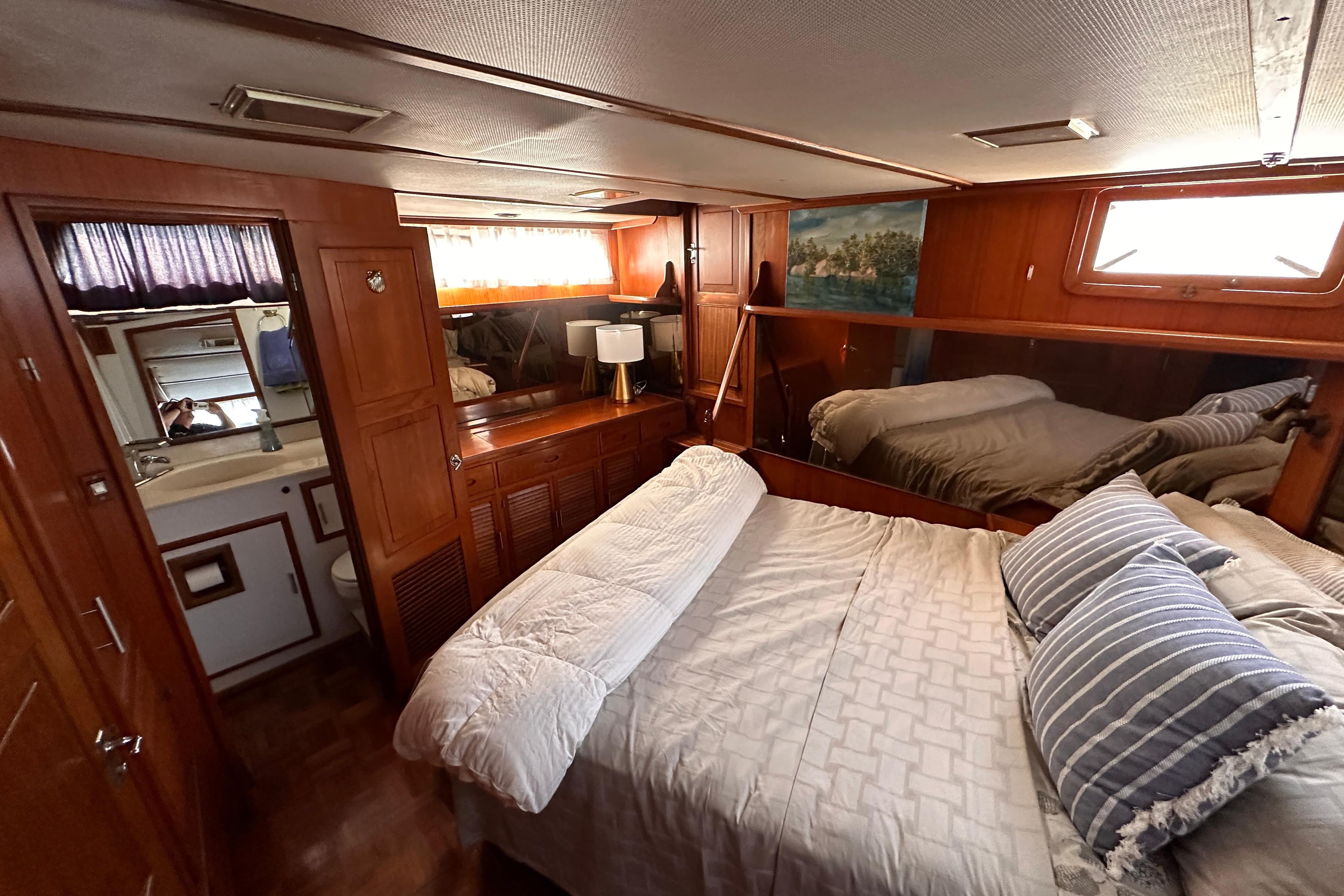 Cozy bedroom in 1987 Marine Trader 47 Tradewinds yacht with wood paneling and ensuite bathroom.