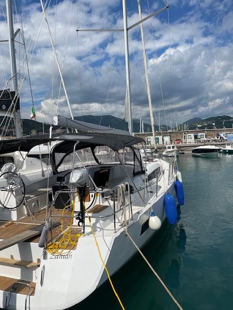2019 Jeanneau 54 yacht docked in a marina under a partly cloudy sky.