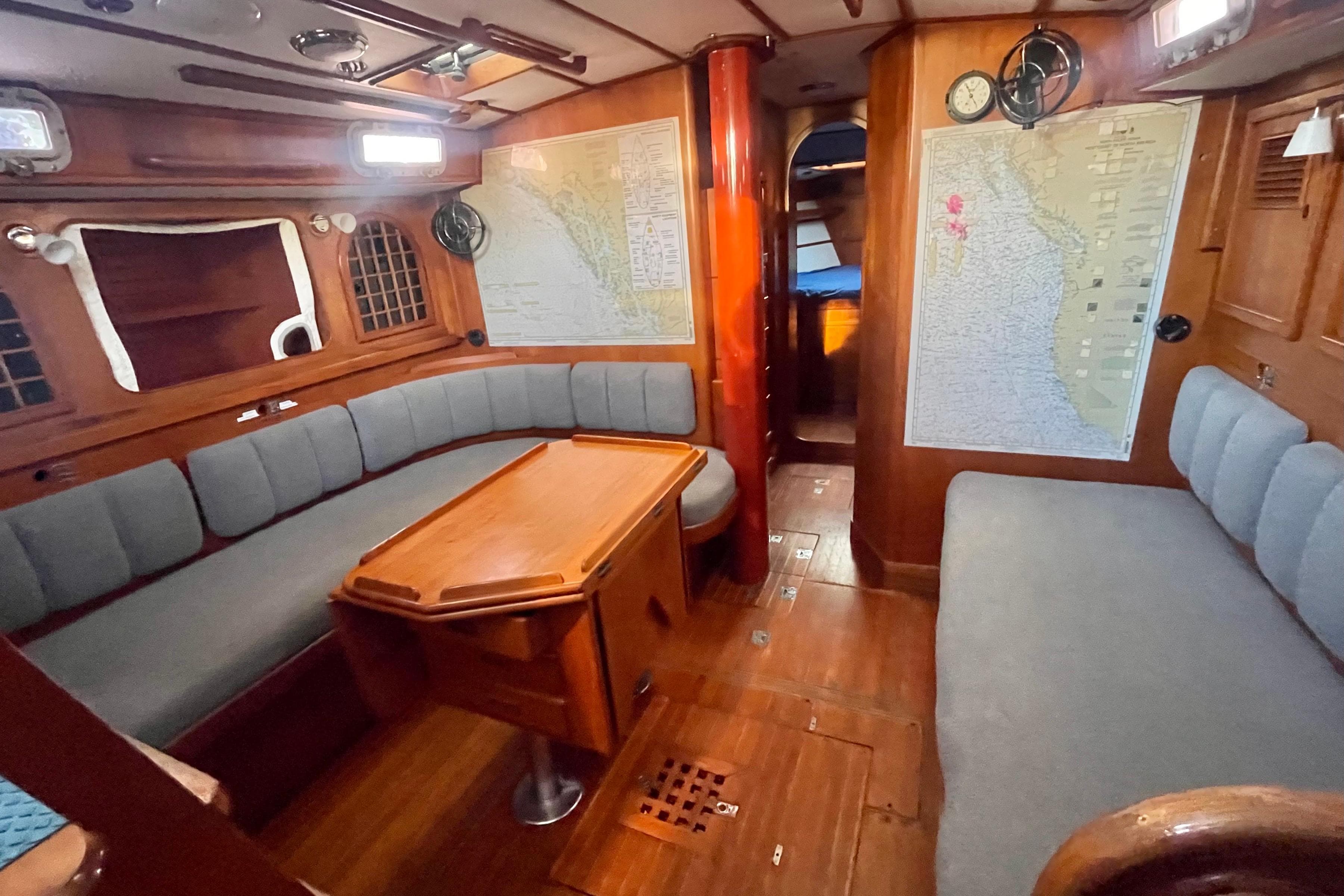 Cozy 1982 Stevens cutter yacht interior with wooden furnishings and nautical maps.