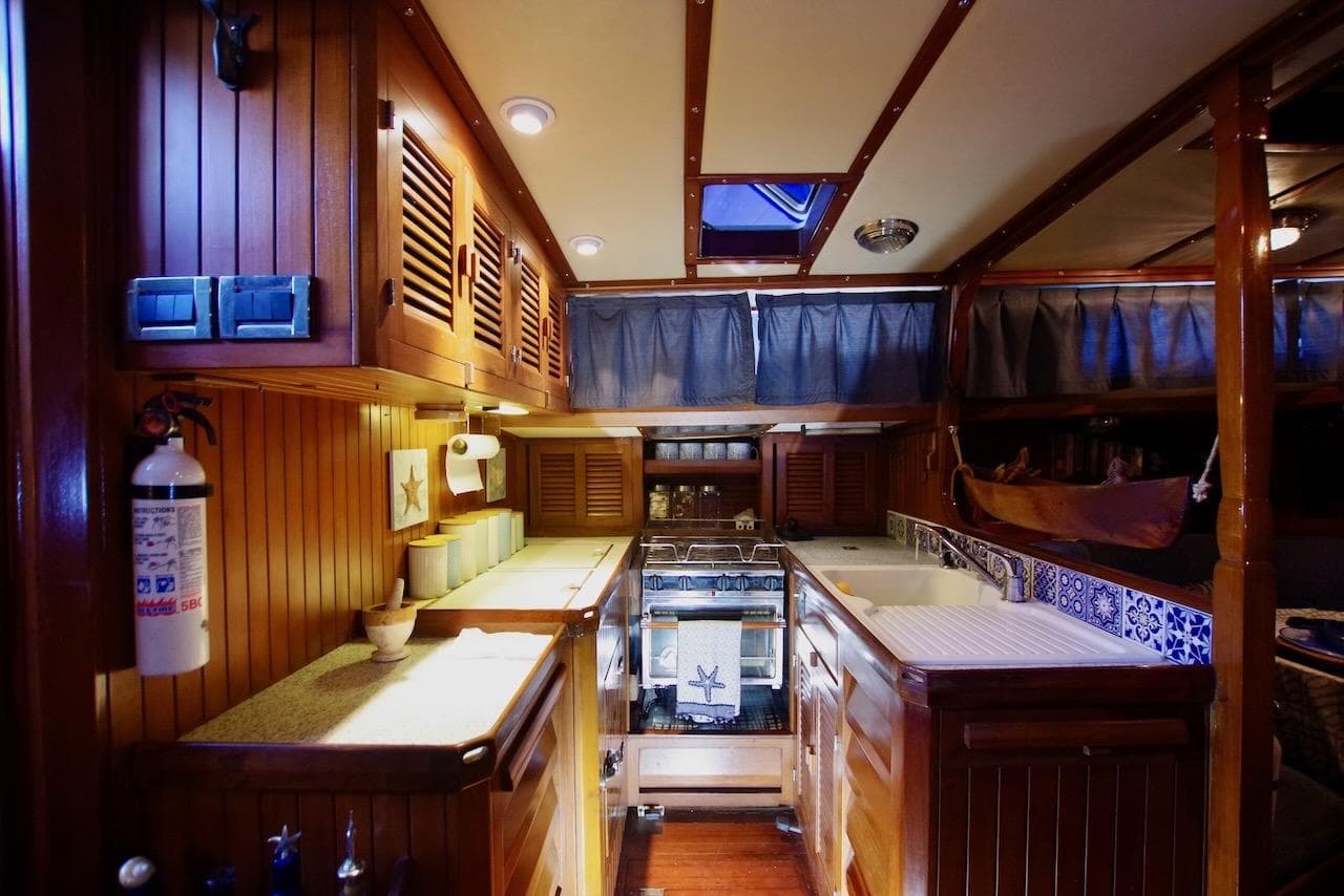 Interior of 1984 Slocum 43 Cutter yacht, featuring a cozy wooden galley with nautical decor.