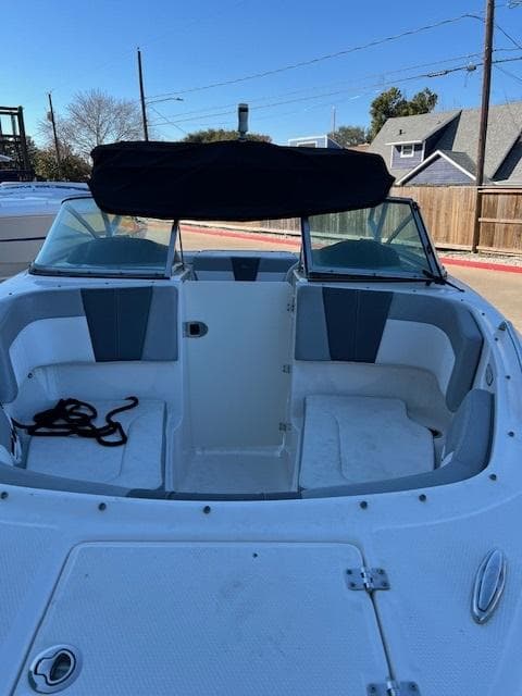2020 Chaparral 23 SSi boat with open bow seating and black canopy.