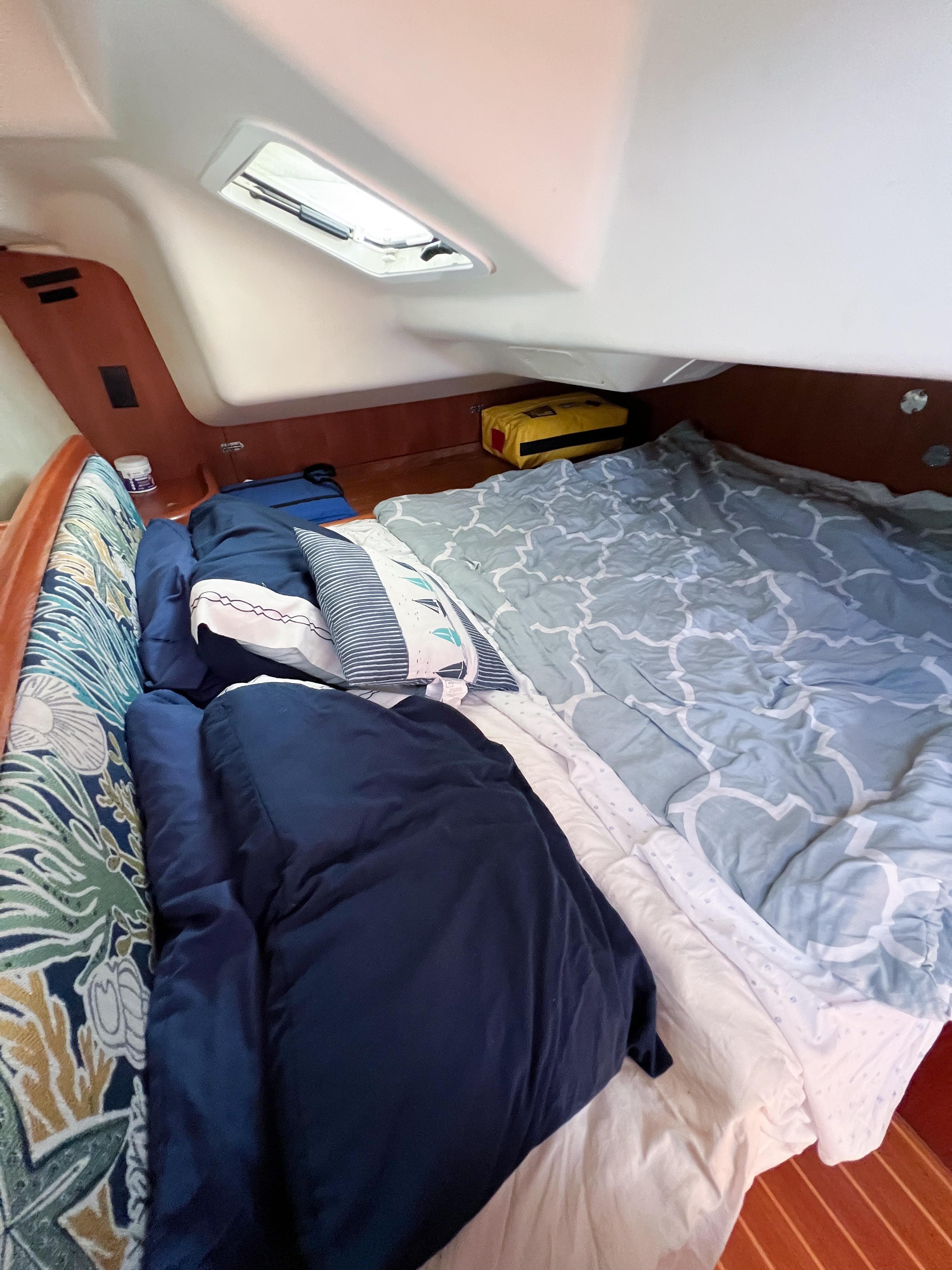 Cozy cabin interior of 2002 Hunter 356 sailboat with bedding and cushions.