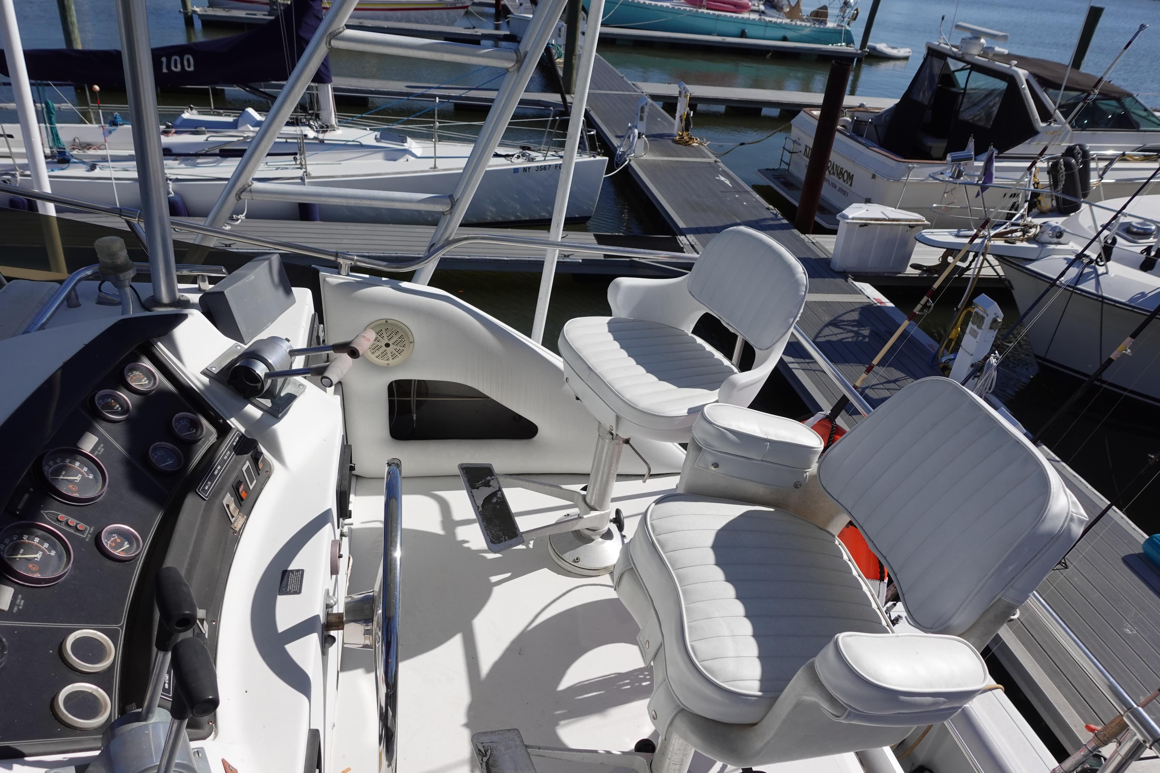 1988 Trojan 10.8 Meter Sedan boat cockpit with white seating and control panel at marina.