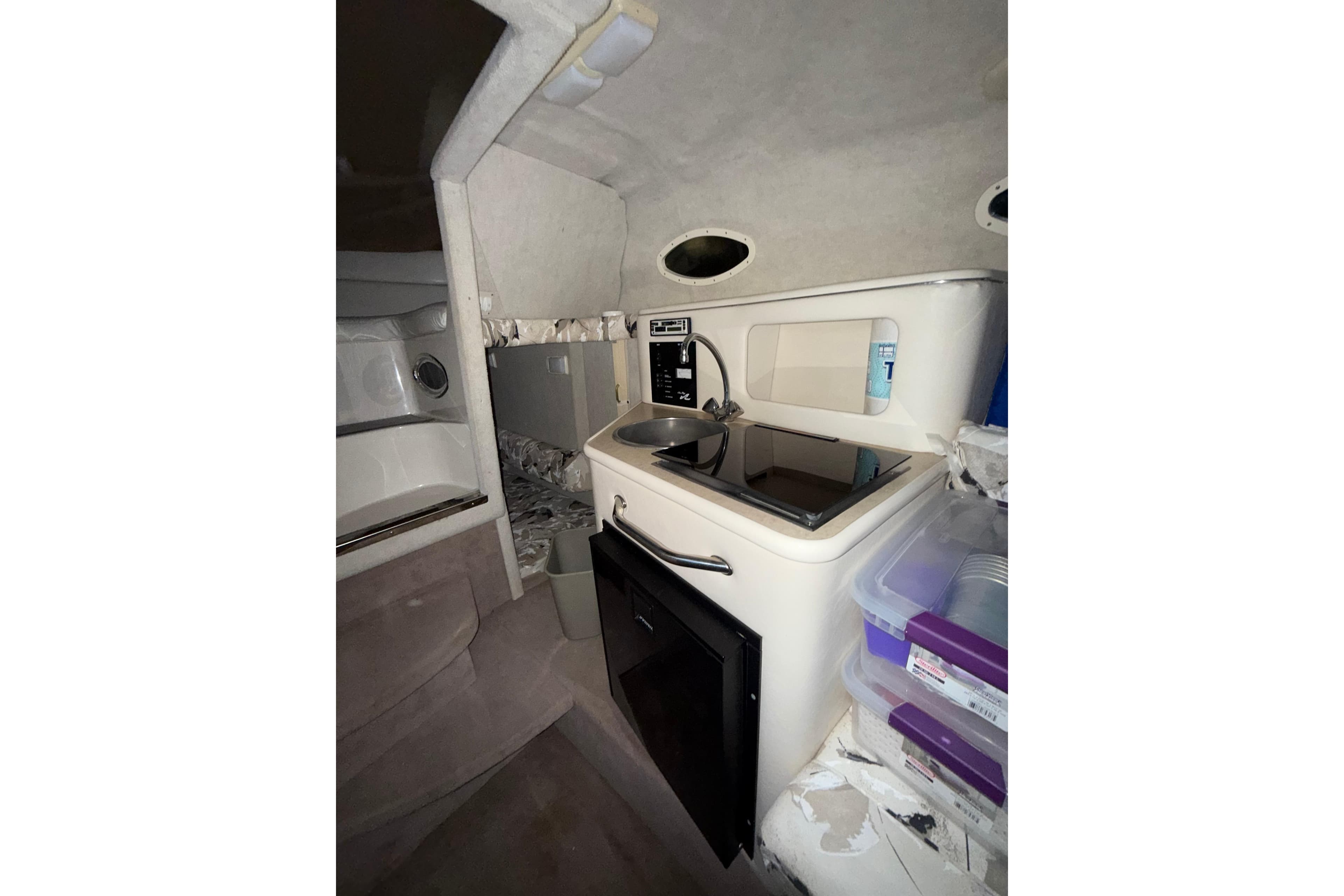 Interior of 2000 Sea Ray 240 Sundancer boat with kitchenette and storage.