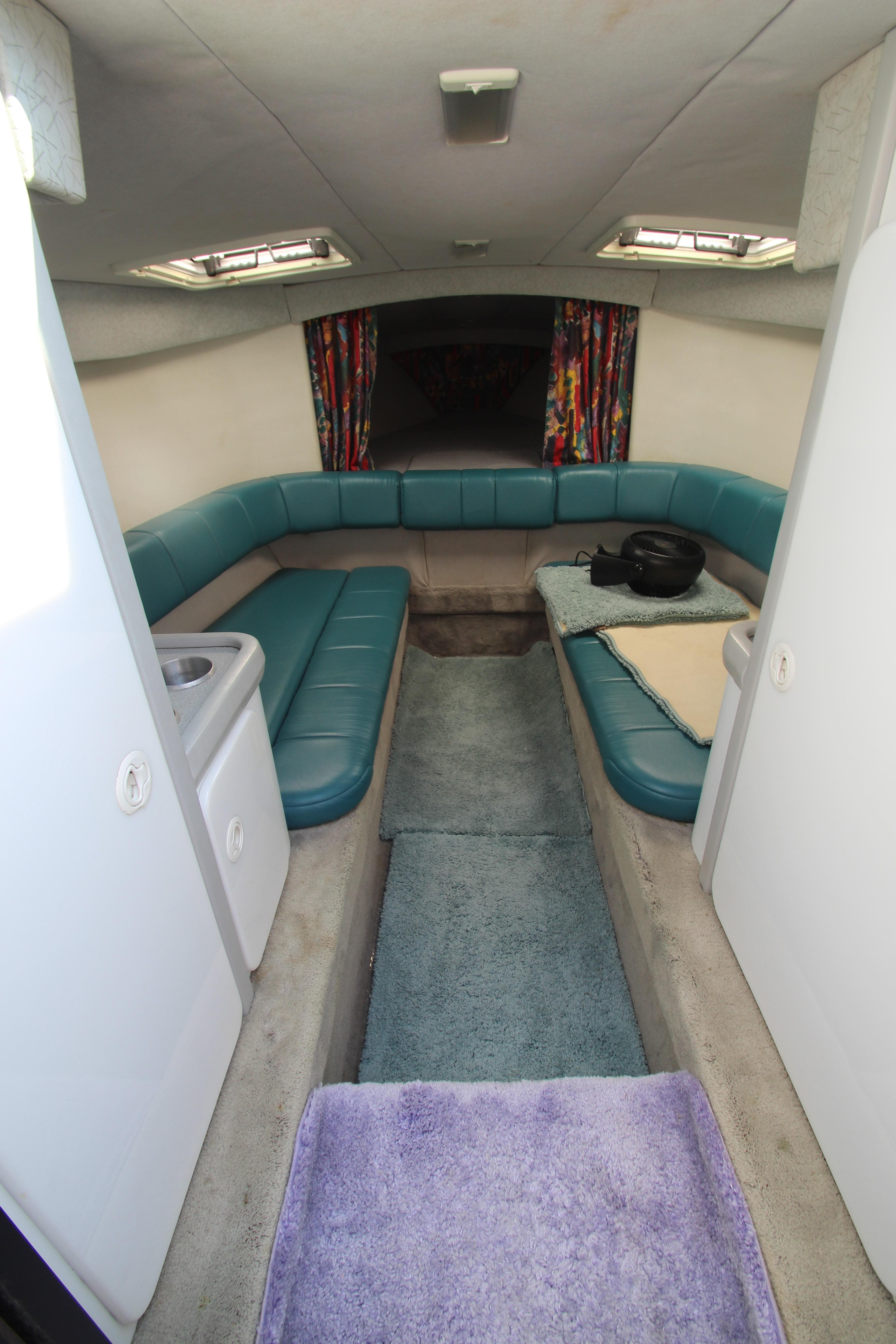 Interior of 1995 Formula SR1 303 boat with teal seating and colorful curtains.