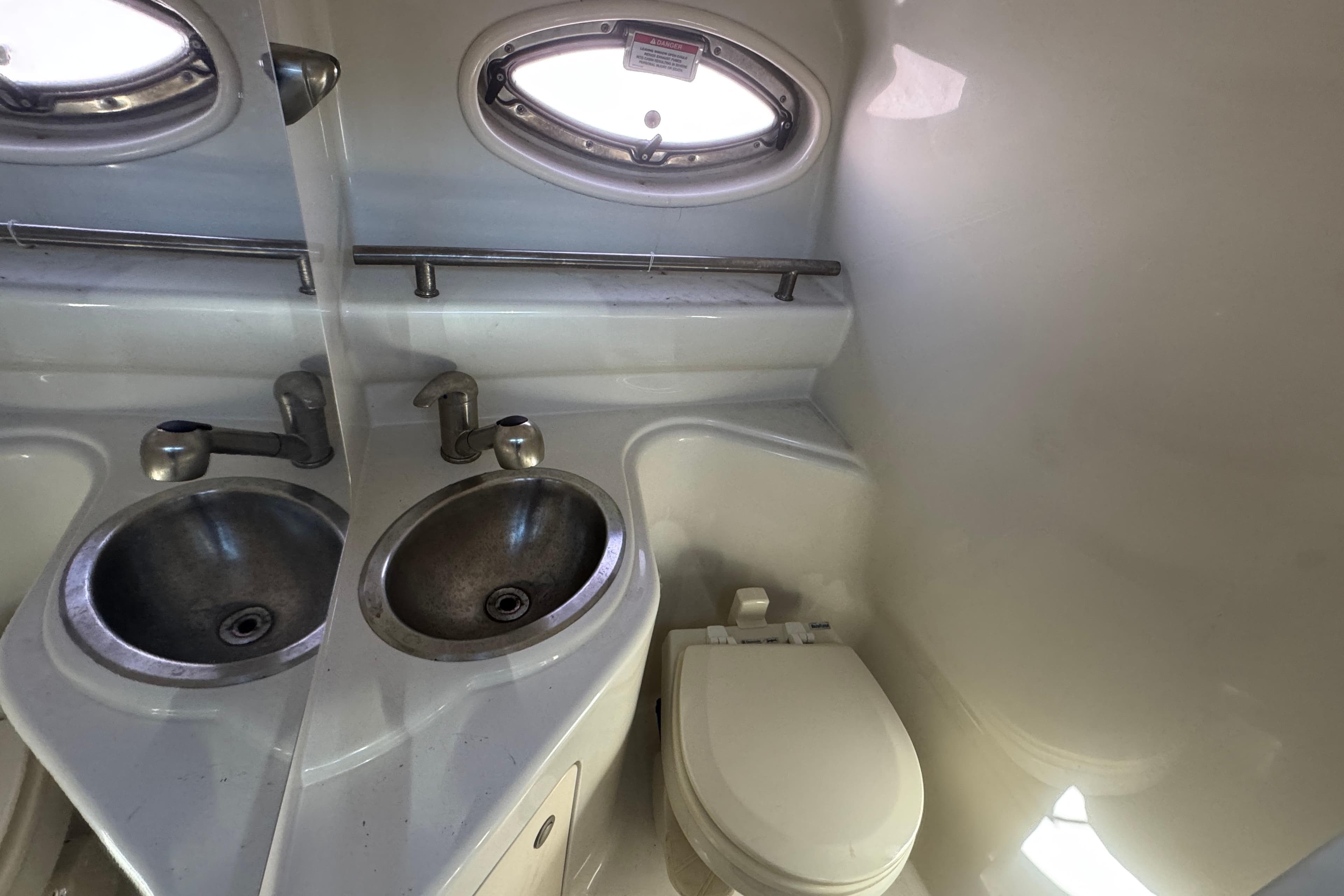 2008 Sea Ray 240 Sundancer bathroom with sink, toilet, and porthole window.
