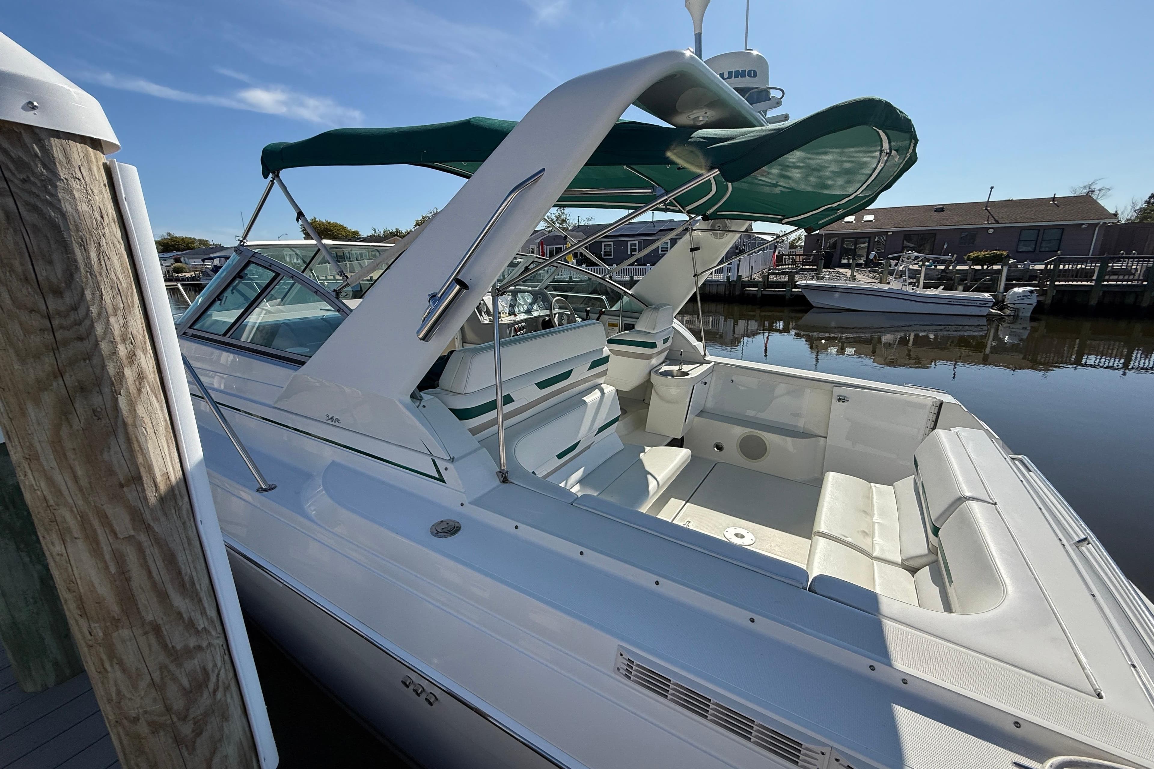 1998 Formula 34 Performance Cruiser docked, featuring spacious seating and green canopy.