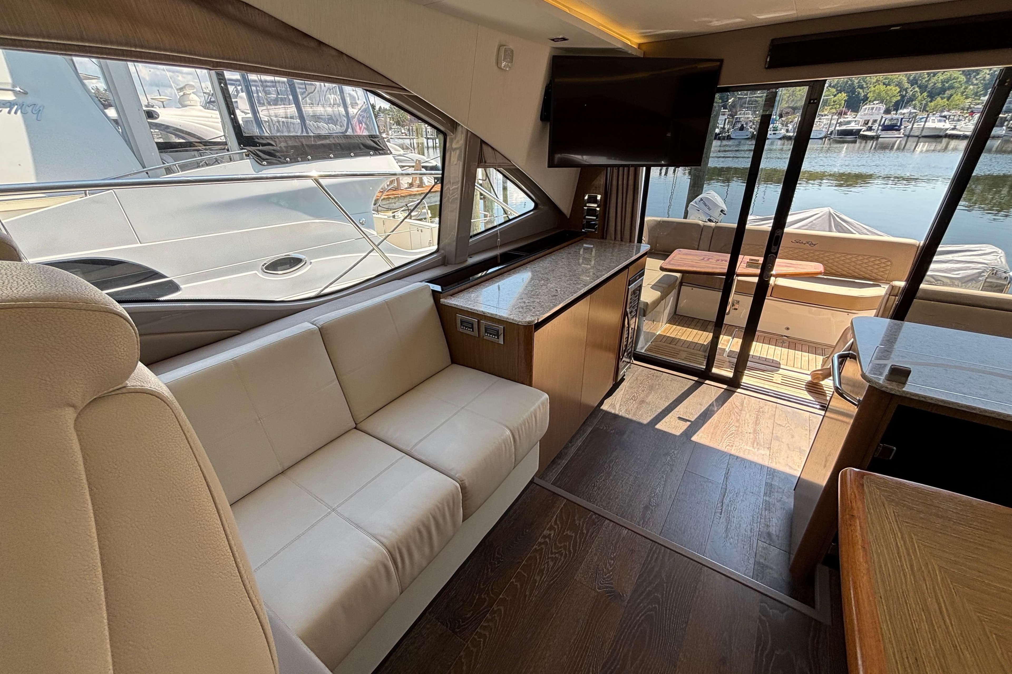 Luxurious interior of 2018 Sea Ray Sundancer 460 yacht with elegant seating and scenic marina view.