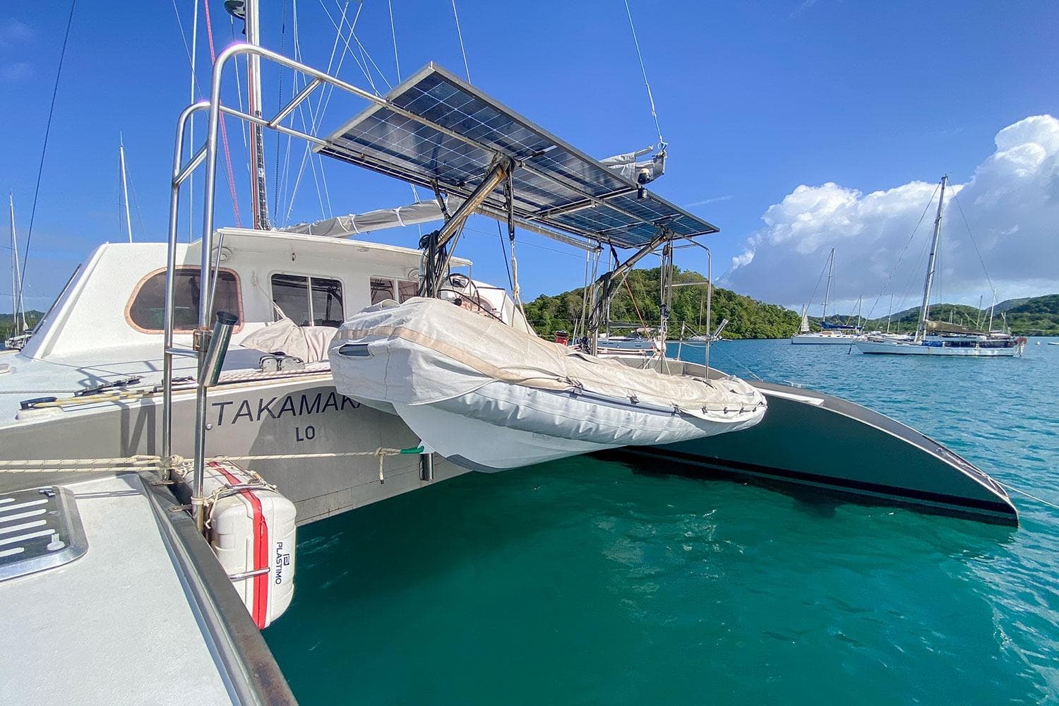 Catamaran BBL CAT 54 (2004) with solar panels and dinghy in a scenic marina.