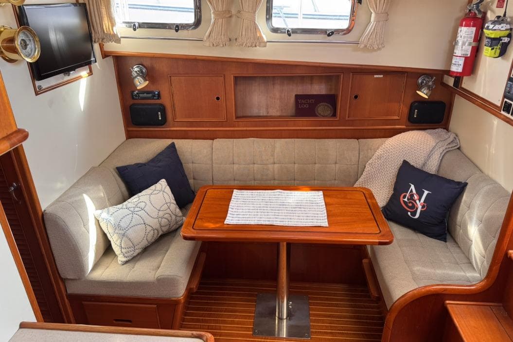 Cozy interior of 1999 Grand Banks 38 Eastbay EX with cushioned seating and wooden table.