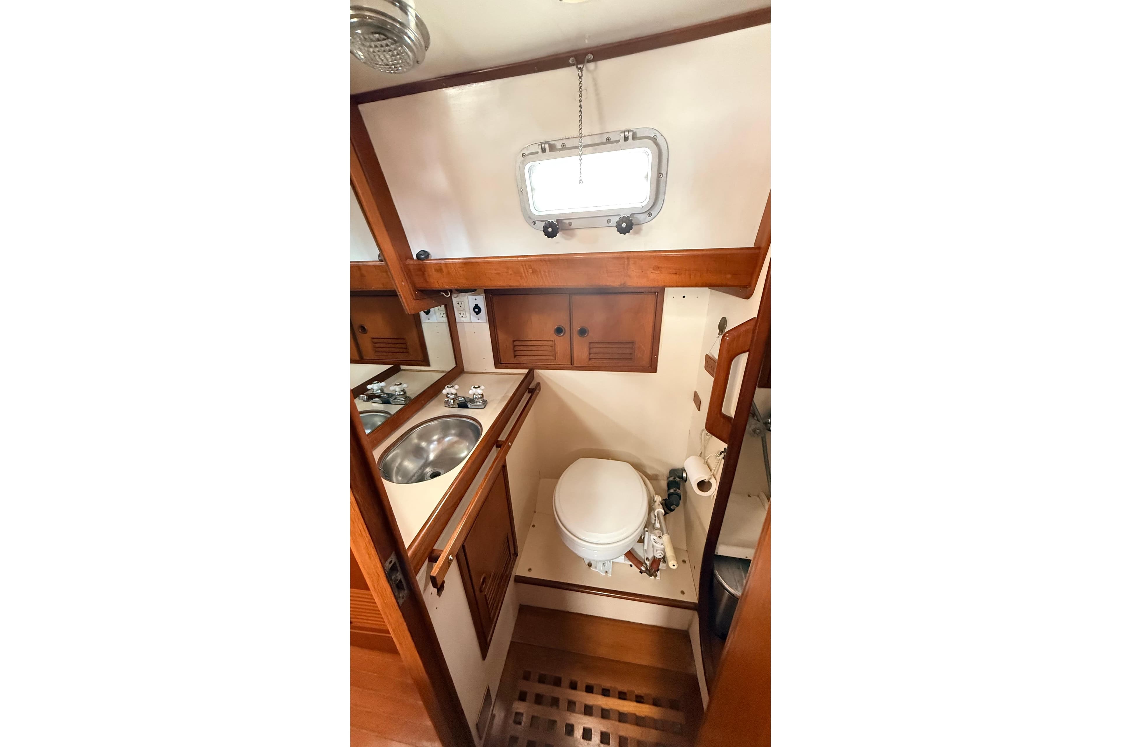 Compact 1983 Tanton 44 yacht bathroom with wooden accents and stainless steel sink.