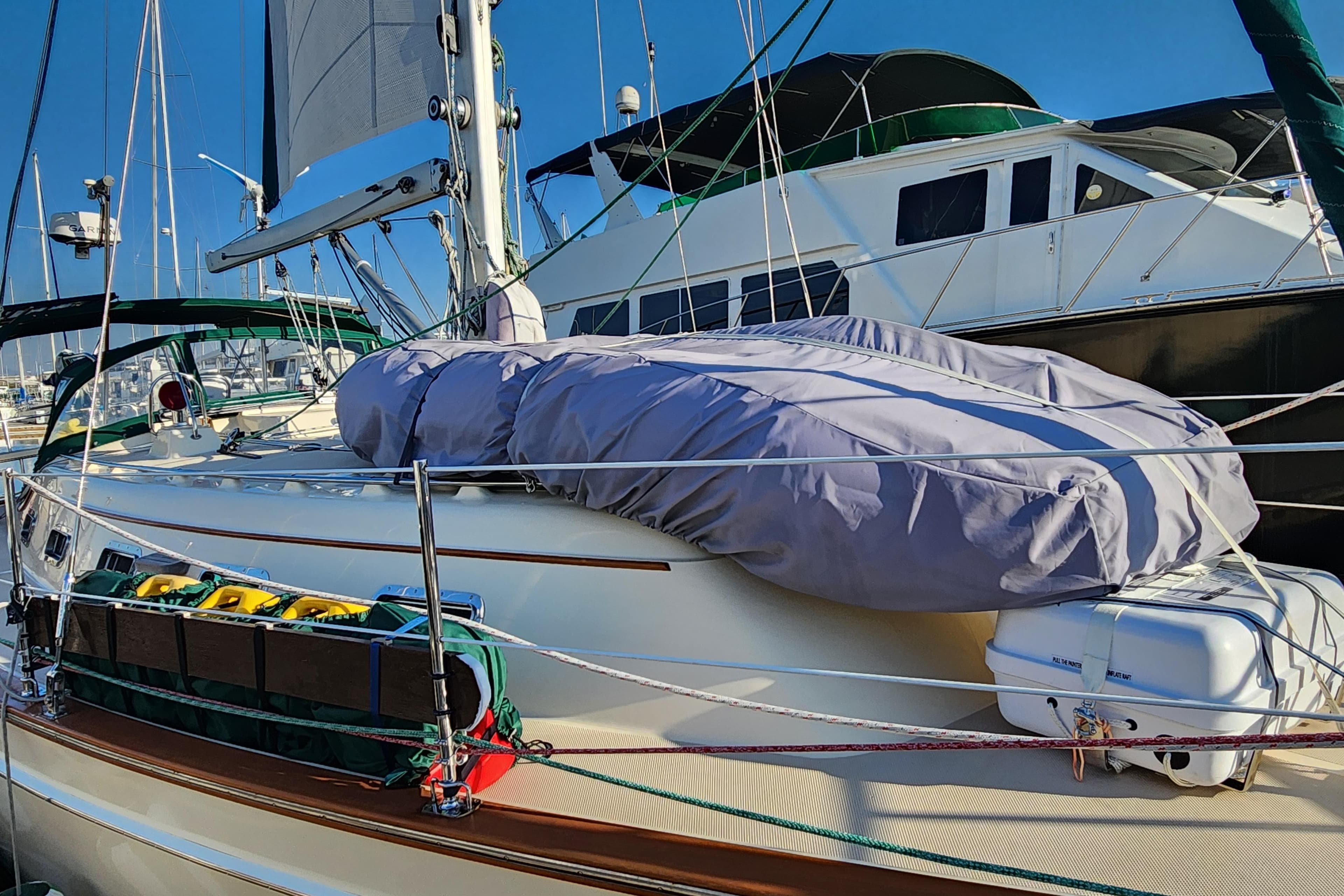 2006 Island Packet 370 sailboat docked, featuring covered equipment and vibrant blue sky.