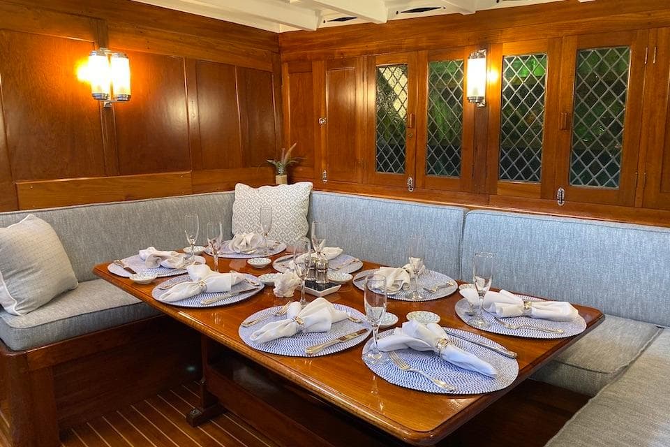 Elegant dining area on 1939 William McMeek Brooks Marine yacht, featuring wooden interiors and table settings.