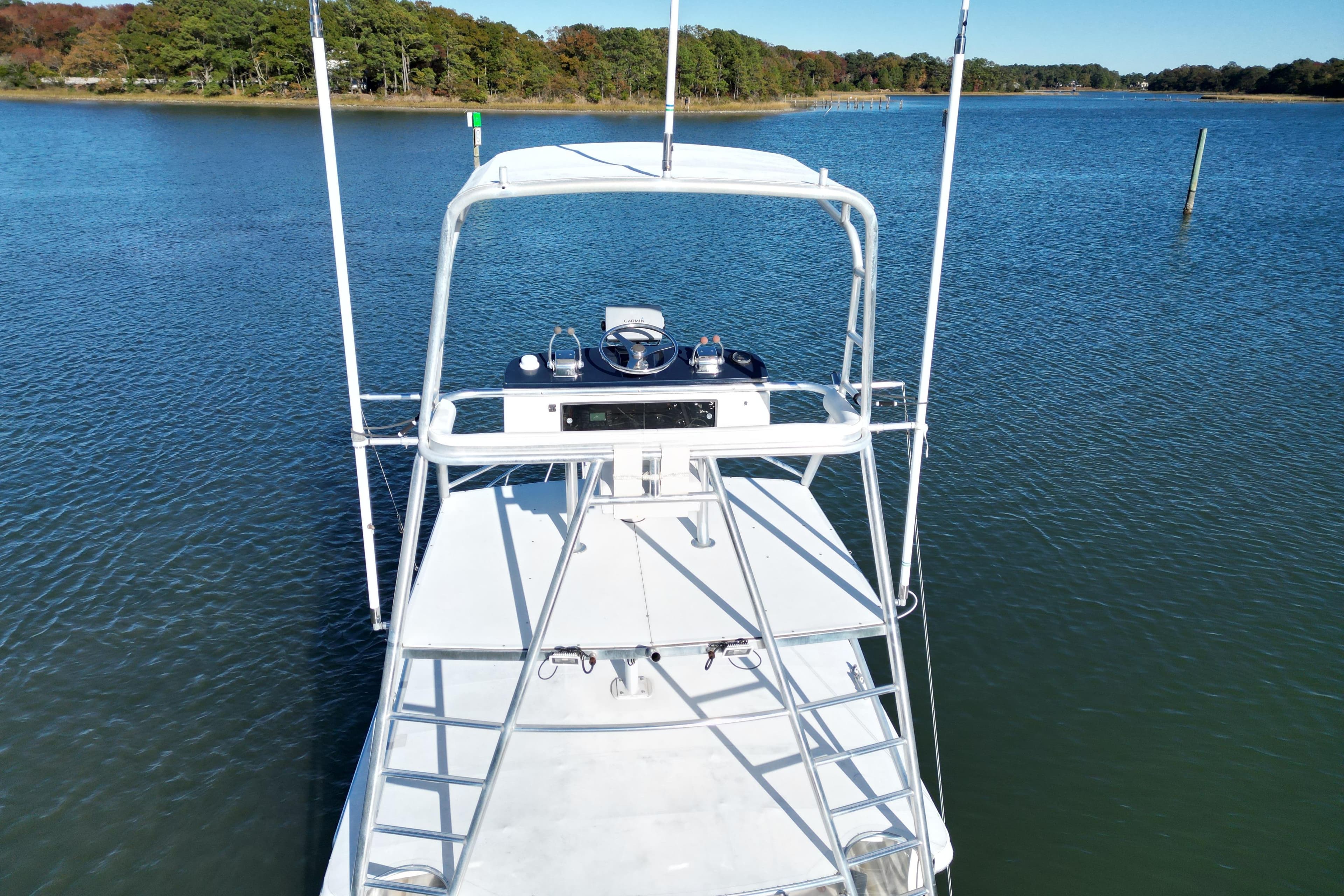 1996 Cabo 35 Express boat on calm water with lush green shoreline.