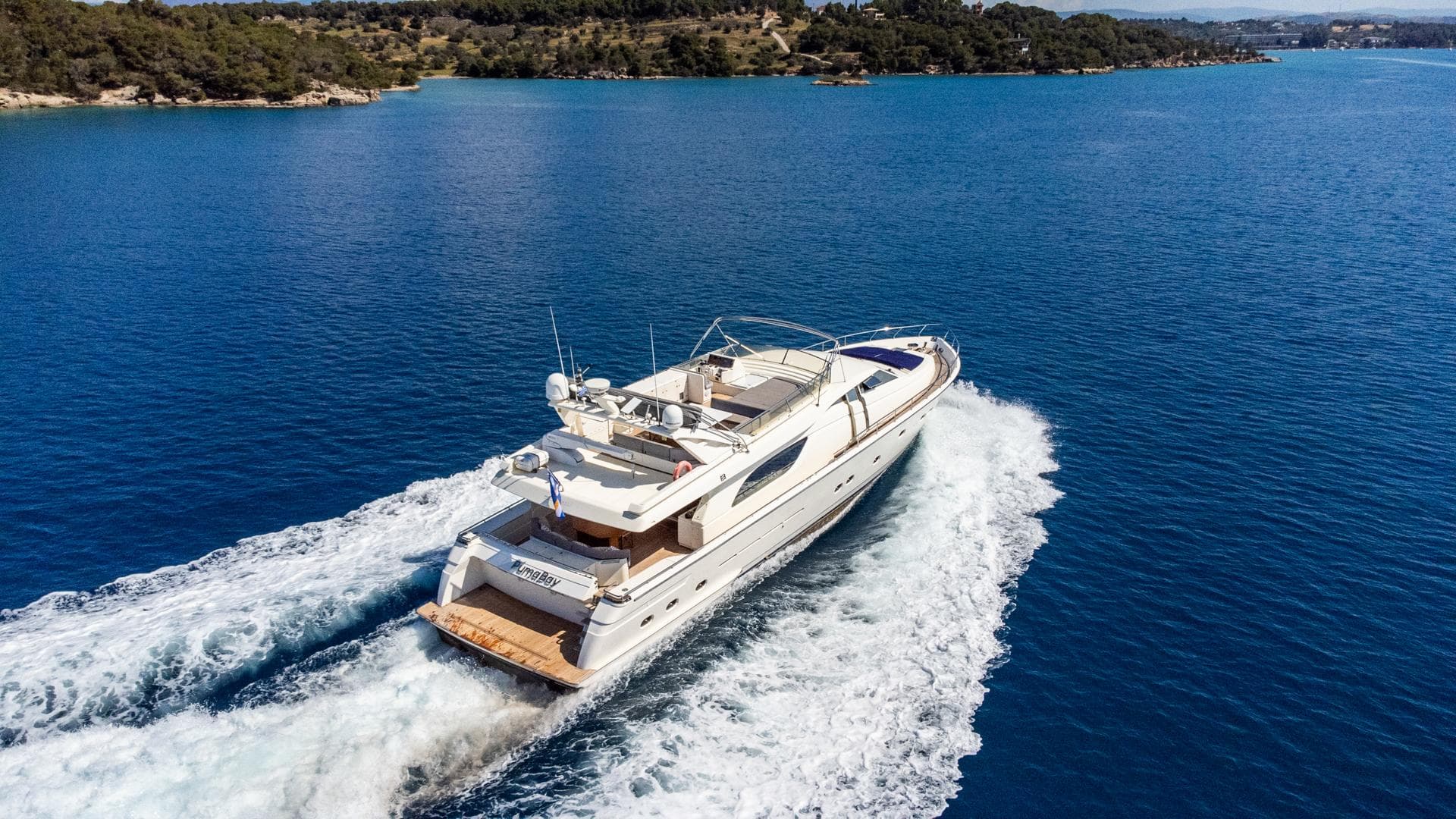 1999 Ferretti Yachts 80 cruising on blue water, surrounded by scenic coastline.
