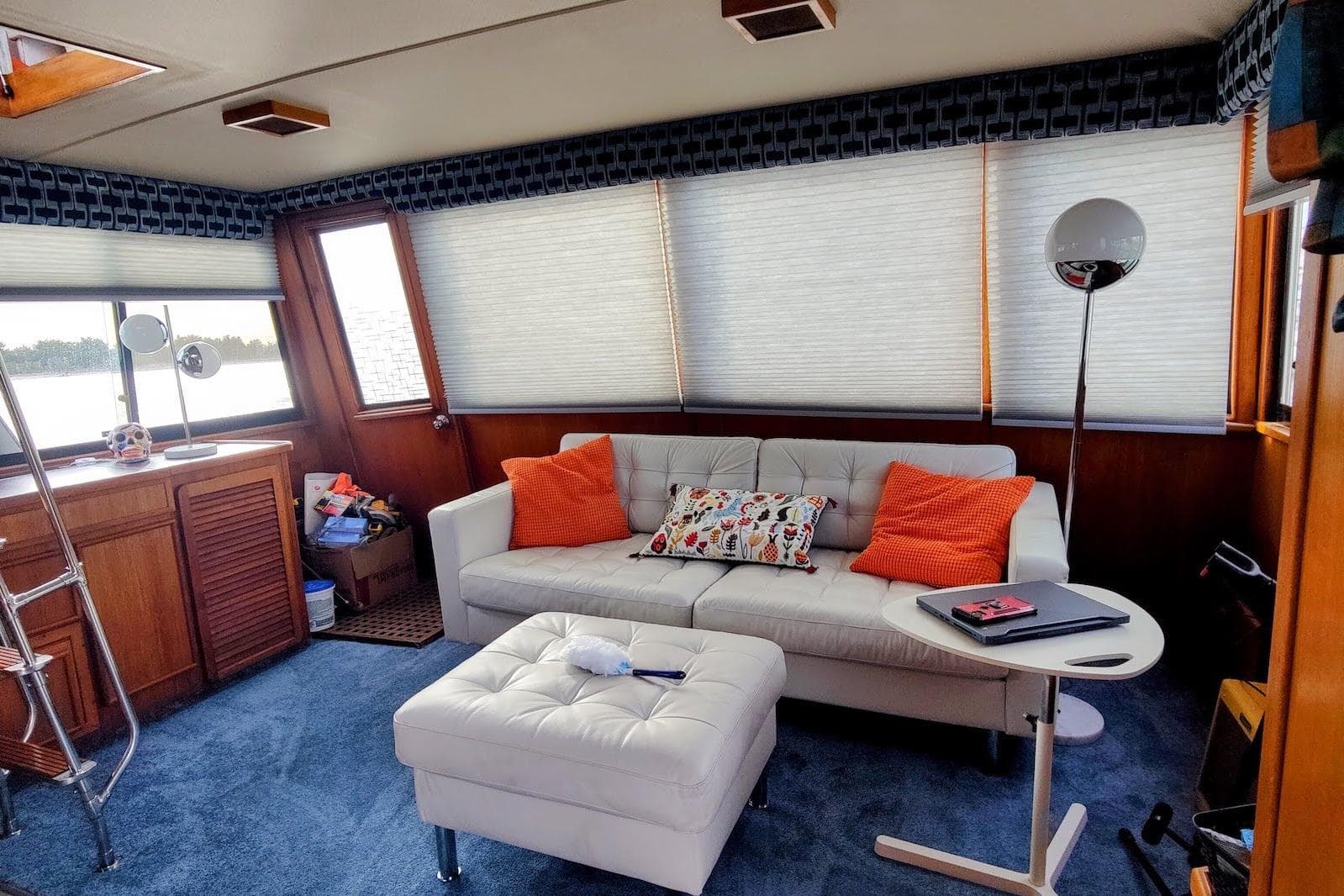Interior of 1988 Chris-Craft 46 Constellation with white sofa, orange pillows, and blue carpet.