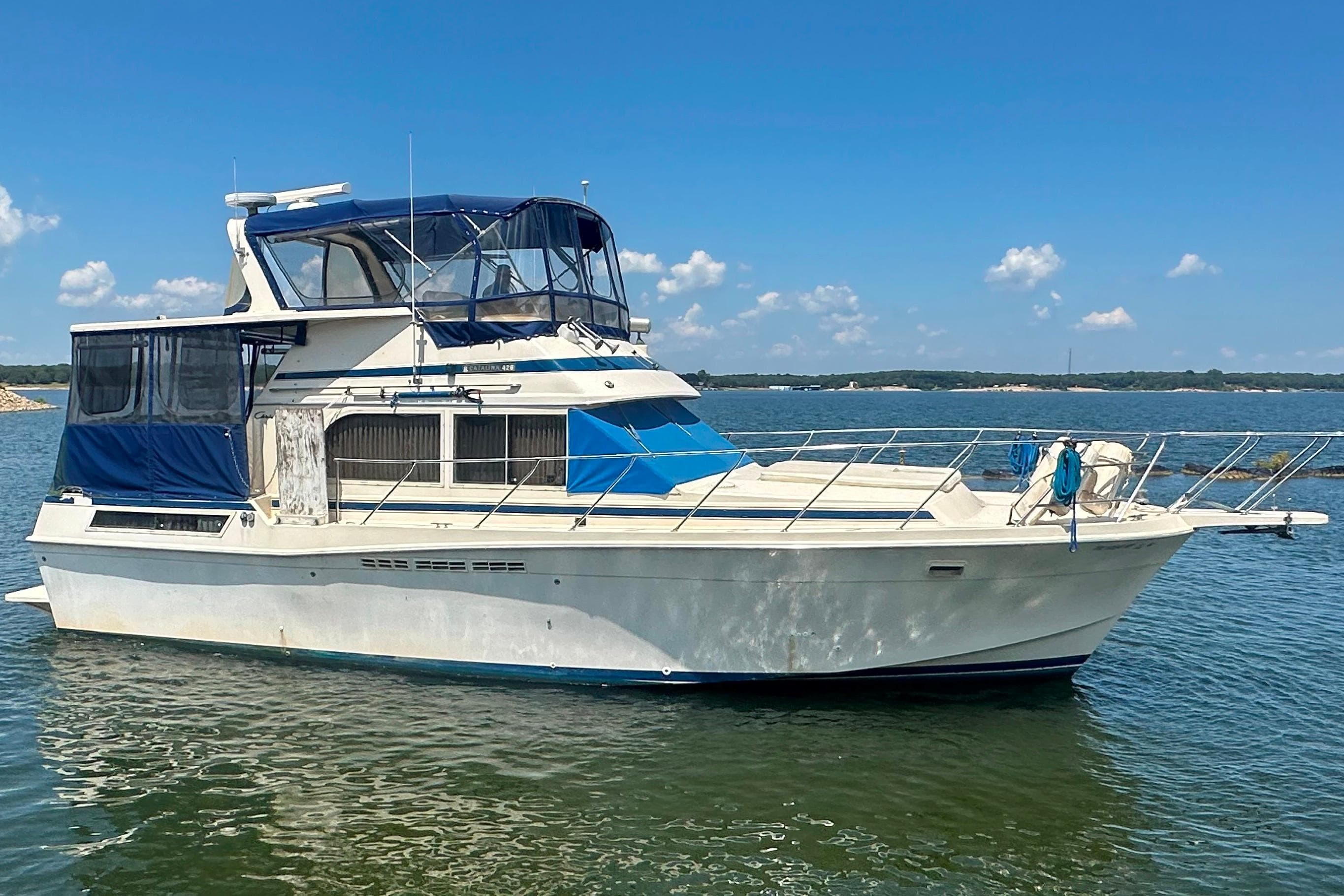 1985 Chris-Craft 426 Catalina yacht on calm water under clear blue sky.