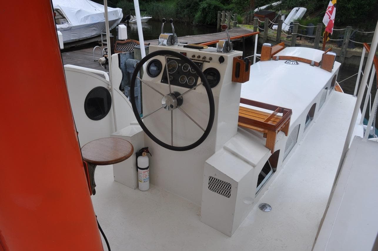 Custom 1987 Sidewheel Paddle Yacht helm with steering wheel and gauges, docked by the water.