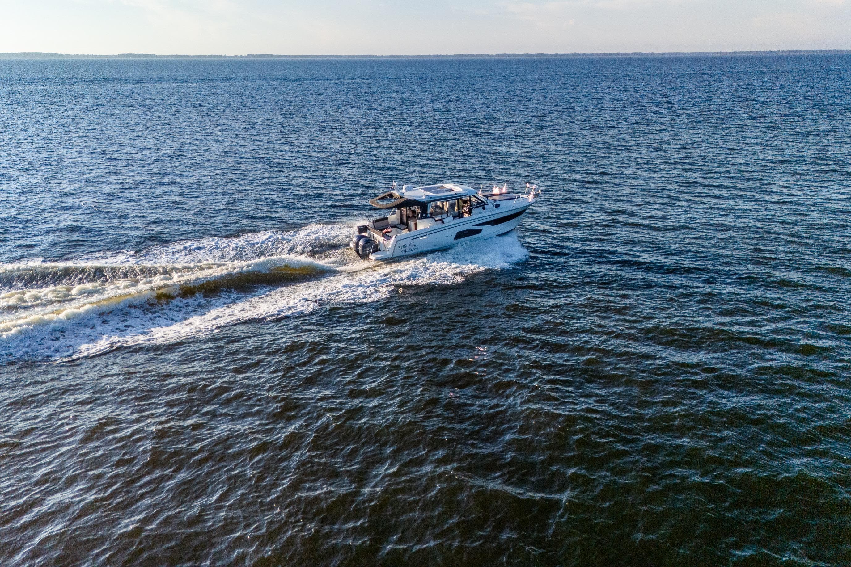 2021 Jeanneau NC 1095 cruising on open water, creating a wake behind.