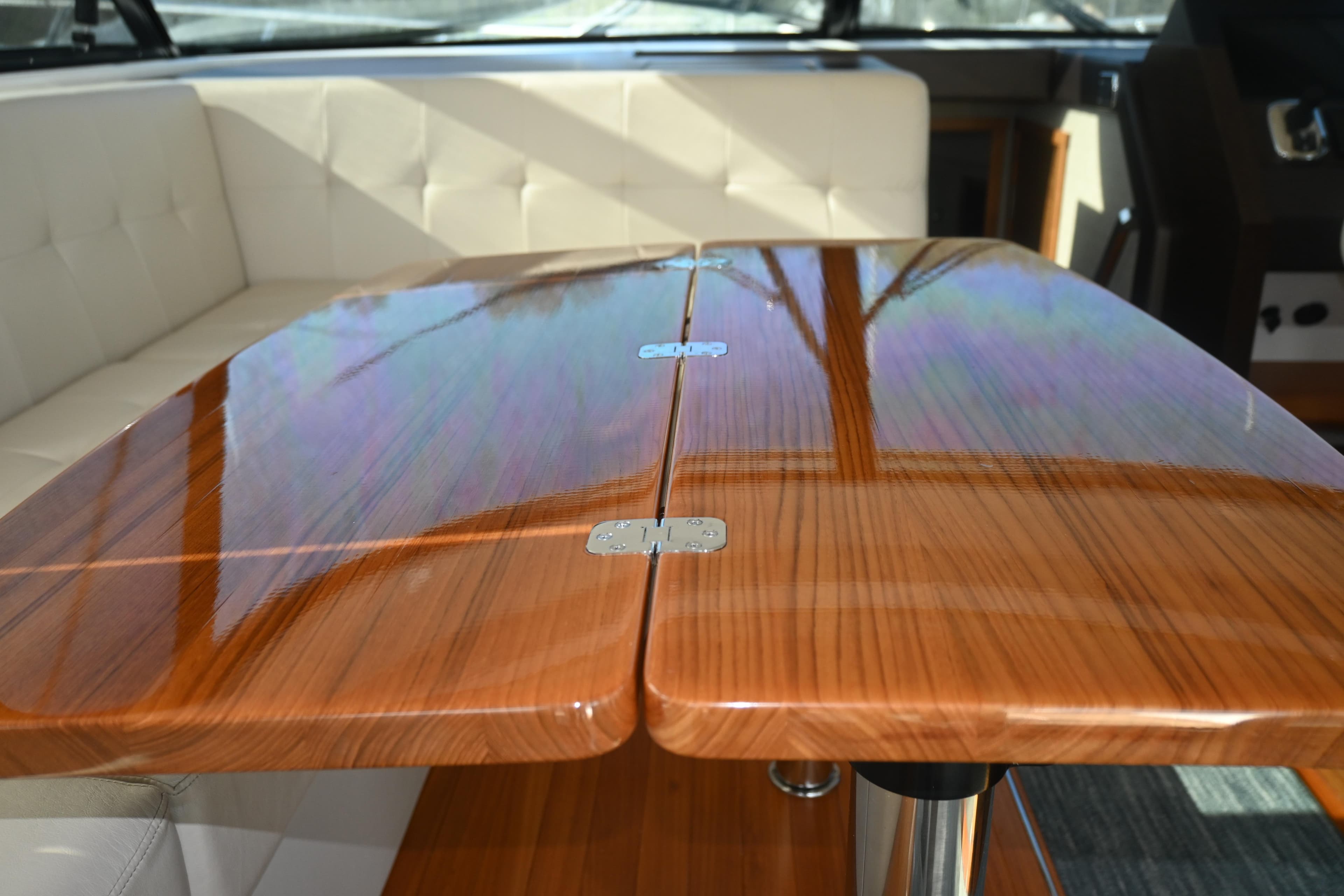 Luxurious interior of 2017 Tiara 44 Coupe with polished wooden table and white seating.