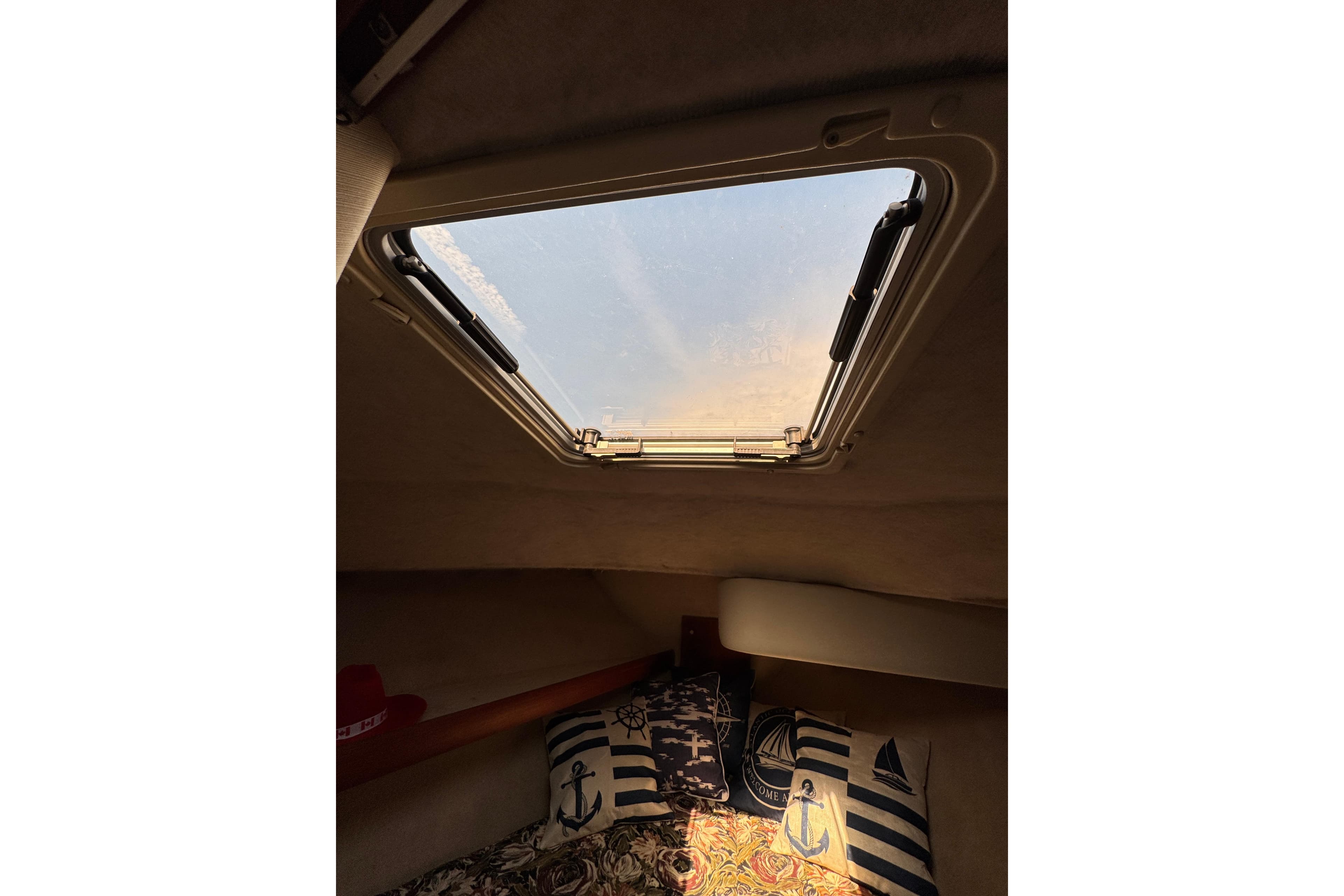 Interior view of 1995 Bayliner 3288 Motoryacht cabin with nautical-themed pillows and skylight.