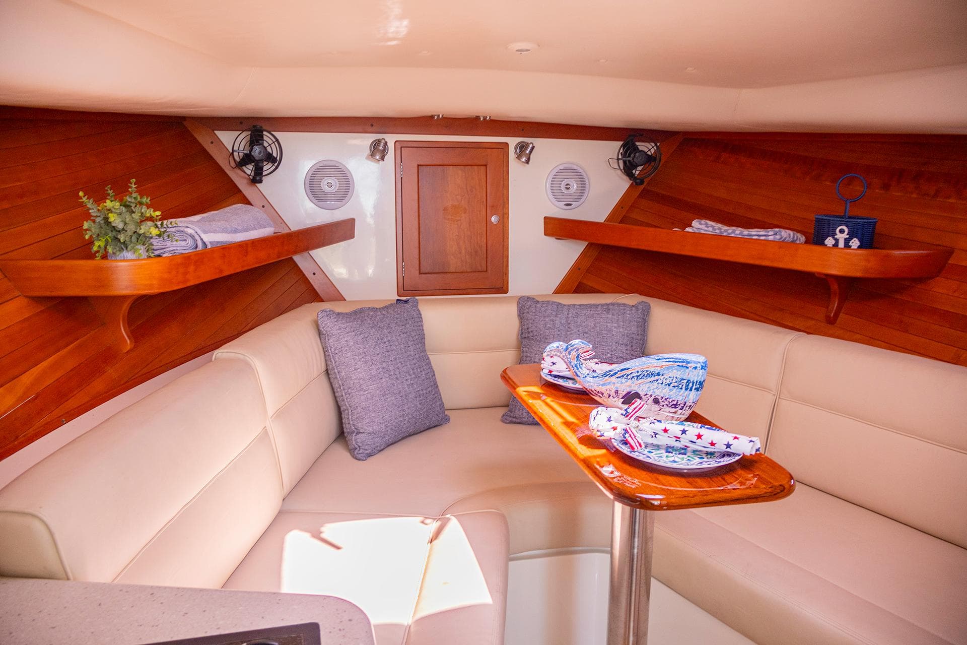 2007 MJM 29z boat interior with beige seating, wooden shelves, and table.