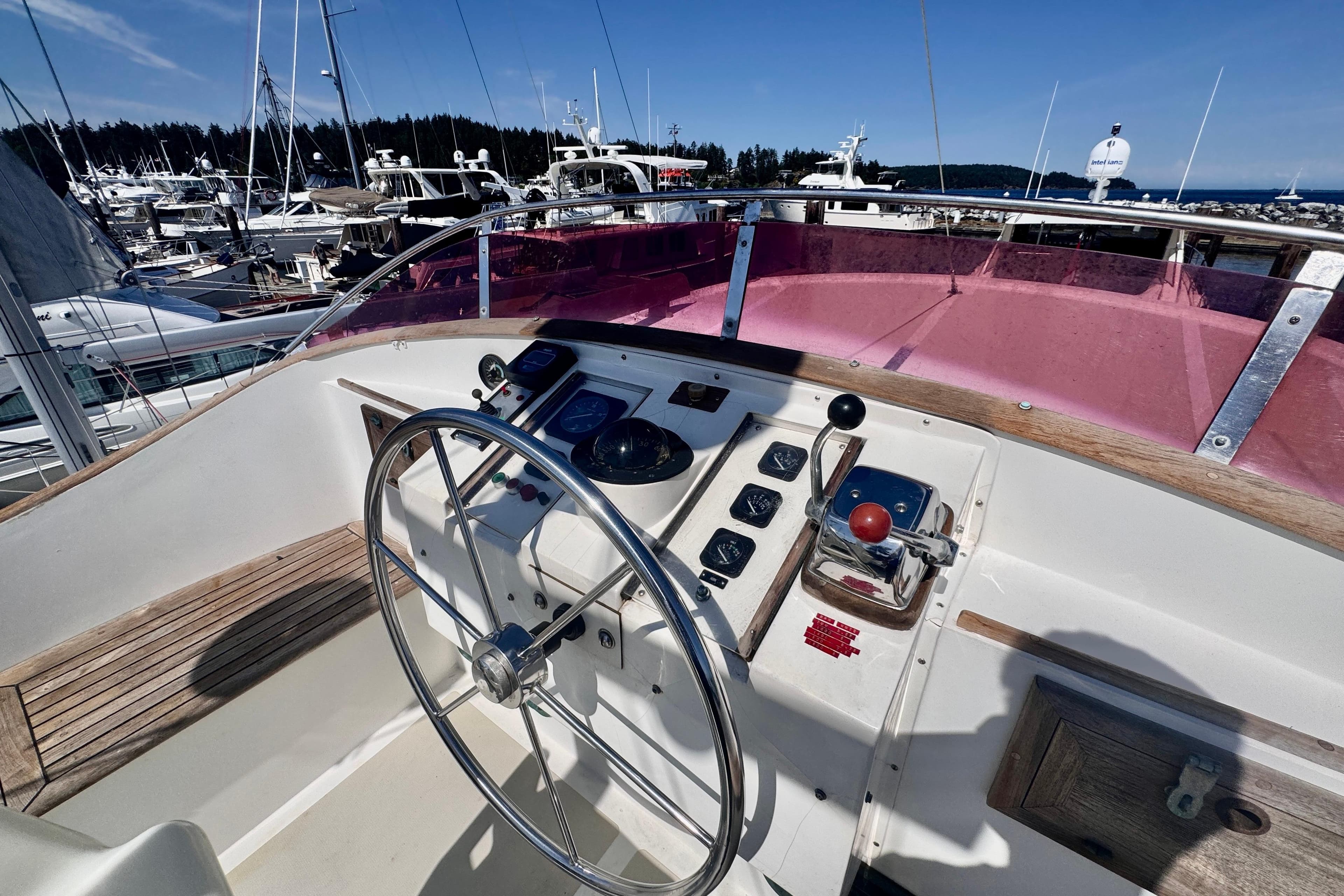 Helm of 1986 Kadey-Krogen 42 yacht with steering wheel and controls, docked in marina.