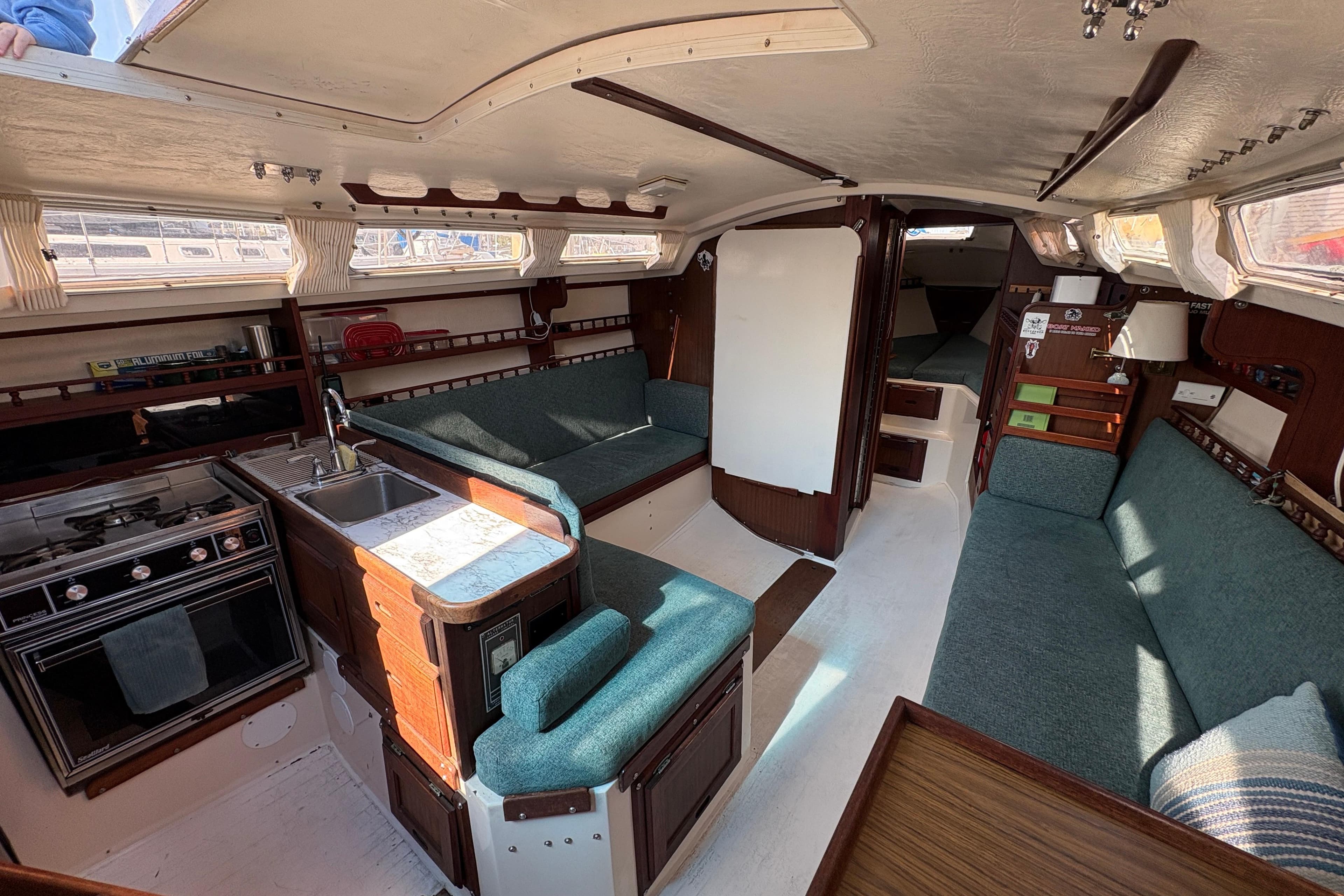 Interior of a 1977 Catalina 30 sailboat with cozy seating and compact kitchen.