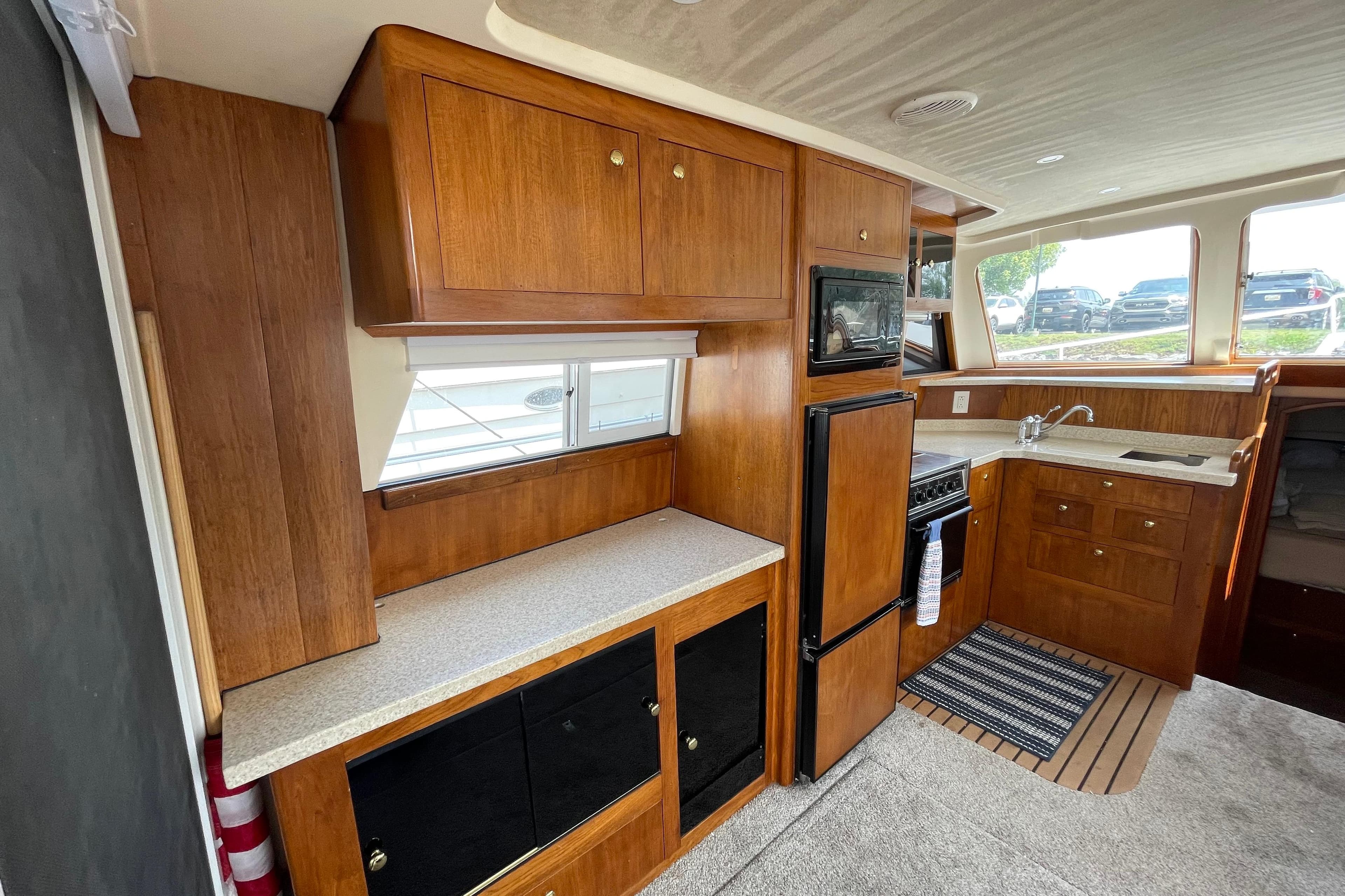 Interior of 2000 Mainship 390 Trawler with wooden cabinetry and compact kitchen area.