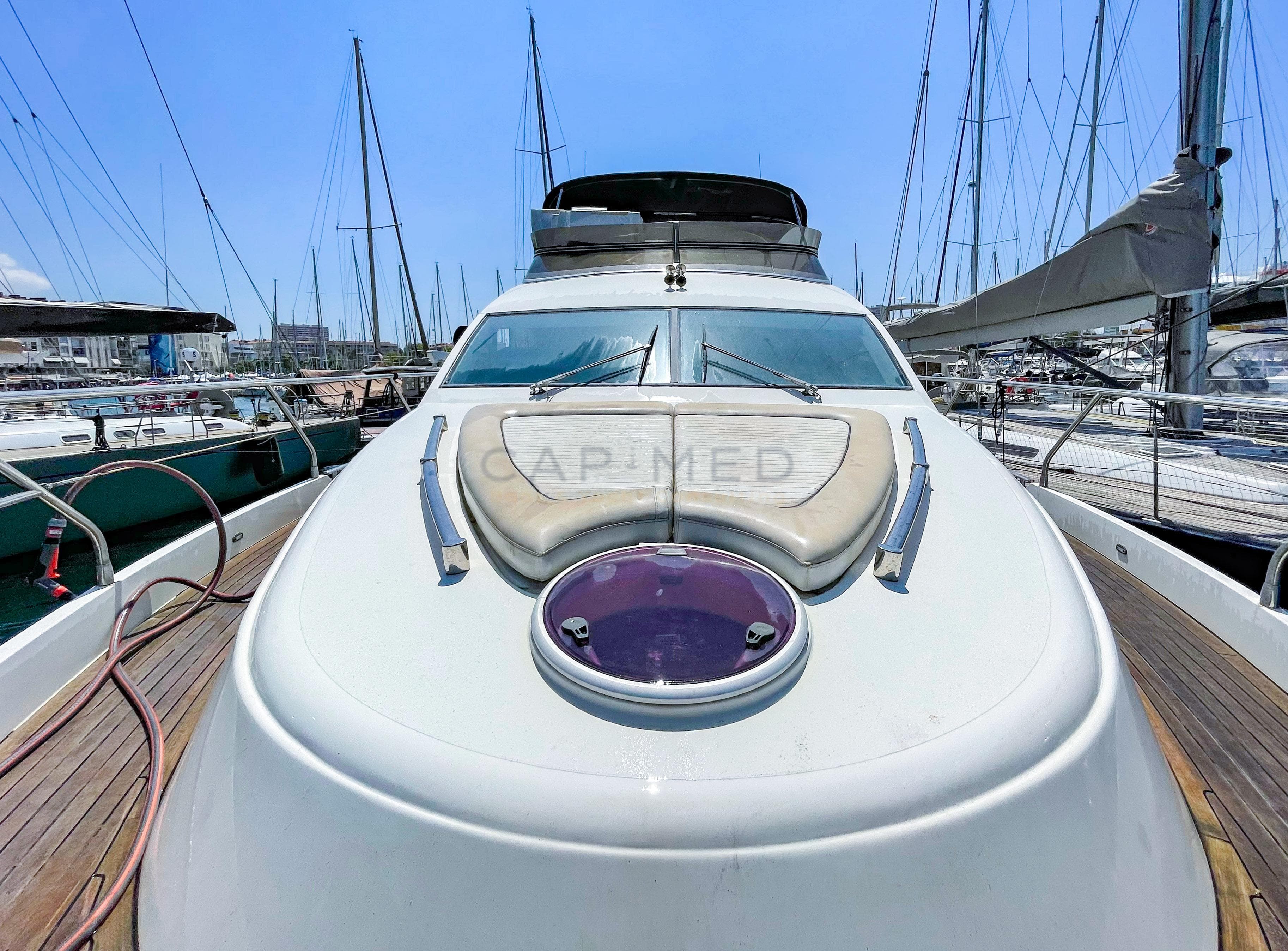 Luxury Pearl 60 yacht from 2006 docked at marina, showcasing sleek design and spacious deck.