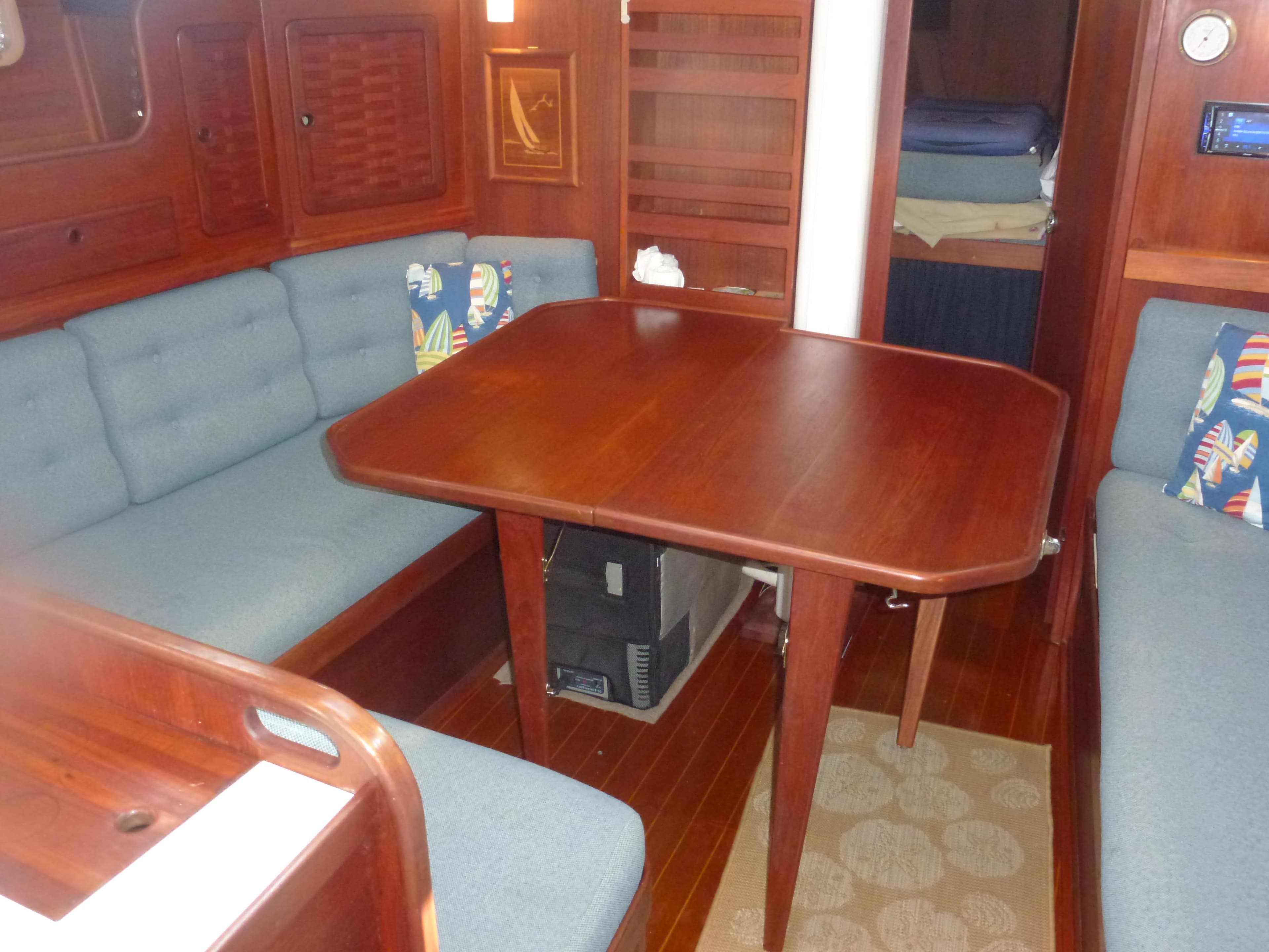 Interior of 1990 Sabre 425 sailboat with wooden dining table and cushioned seating.