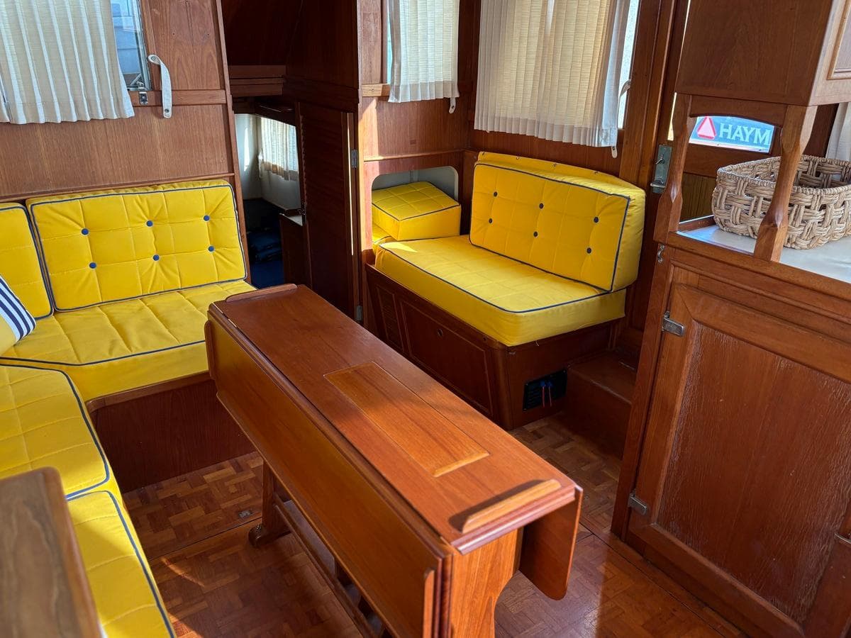 Interior of 1986 Grand Banks 36 Classic with yellow cushioned seating and wooden table.