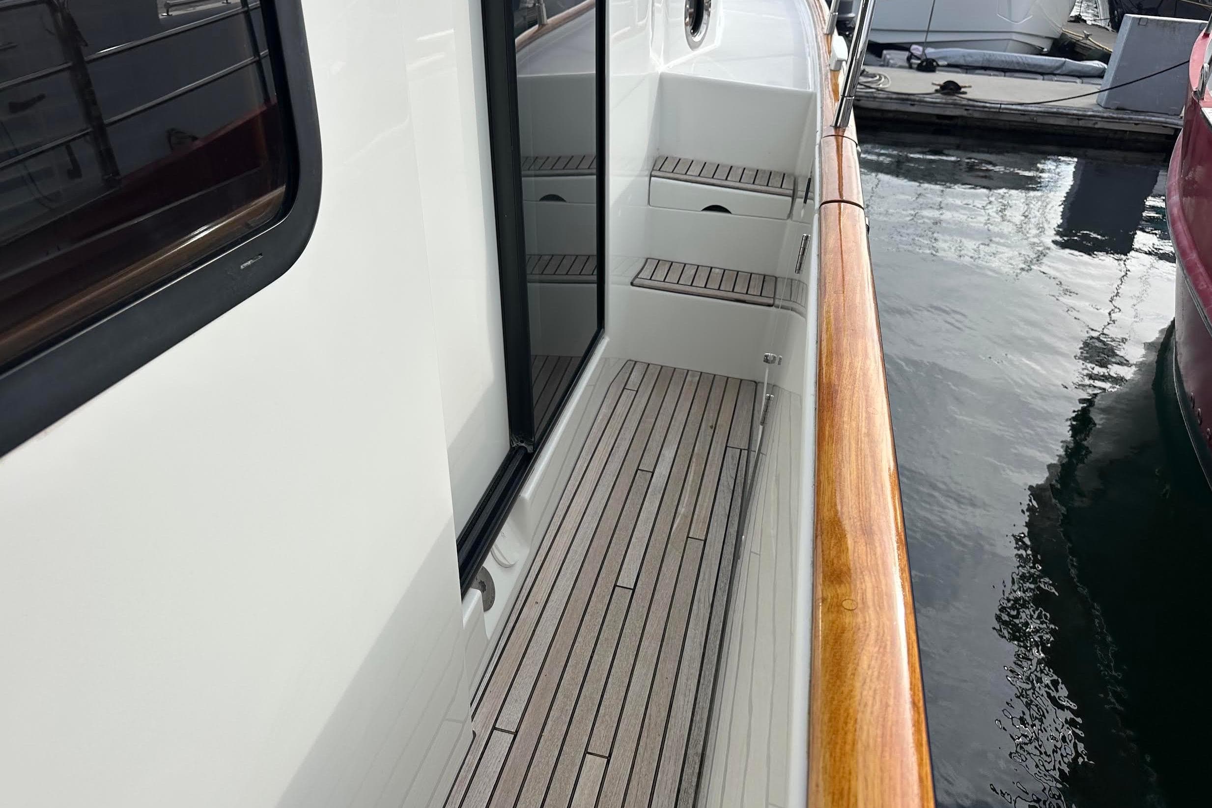 2015 Beneteau Swift Trawler 44 deck with wooden railing, docked at marina.