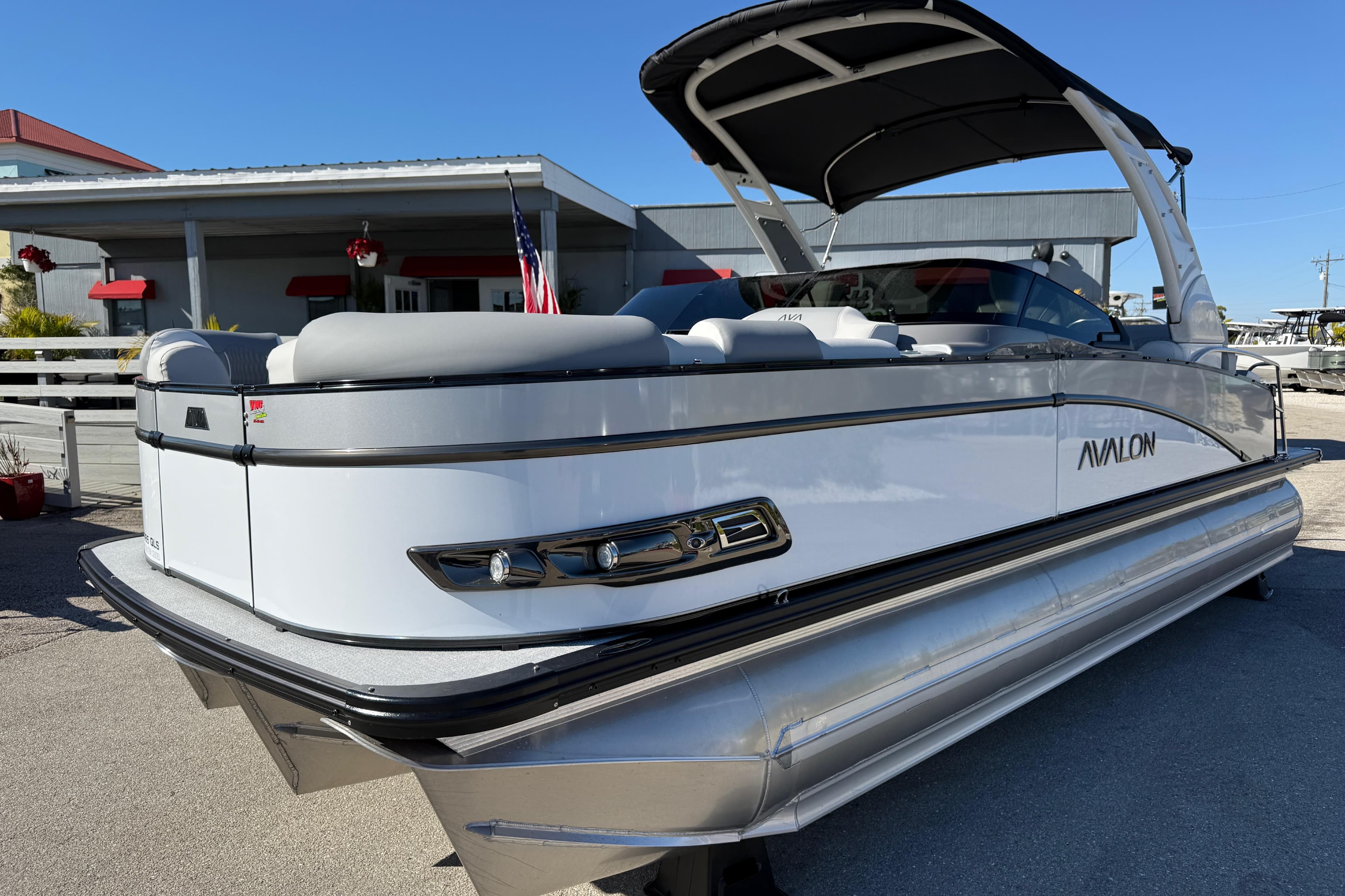 2026 Avalon 2385 Catalina Windshield Quad Lounger, Tri Toon, high-performance boat in a marina setting.