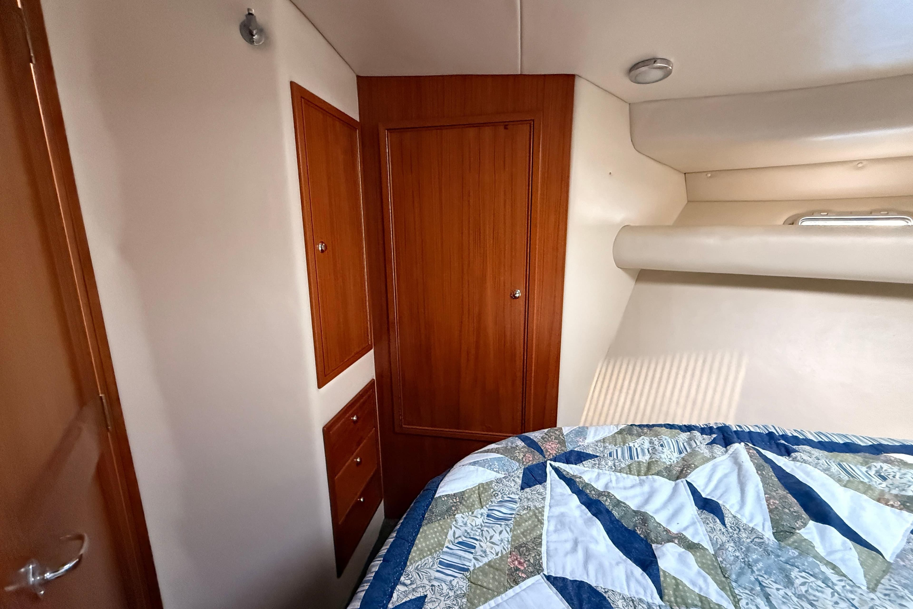 1999 Riviera 34 Convertible cabin interior with wood paneling and quilted bedspread.