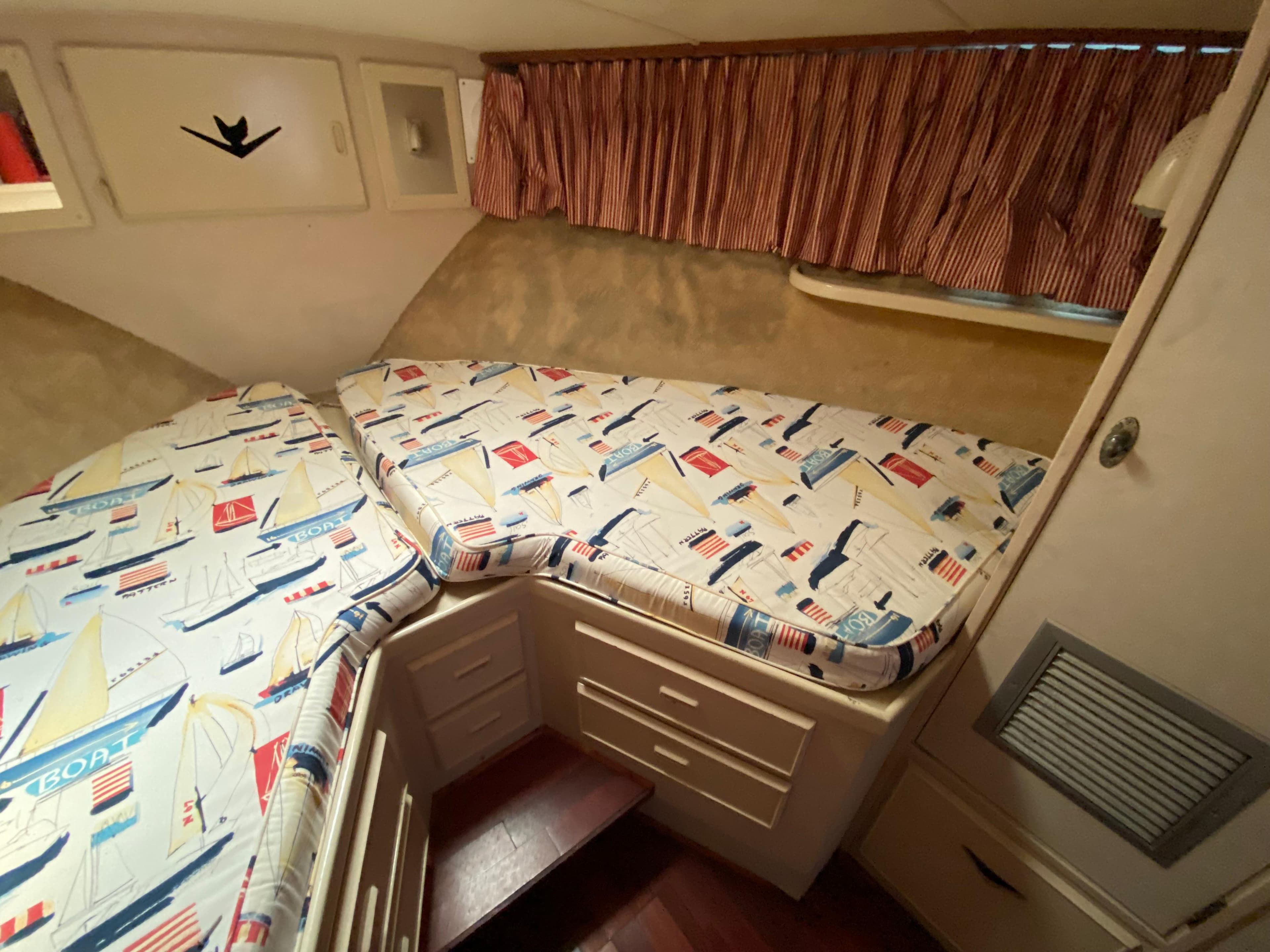 Cozy cabin interior of 1982 Bertram 46.6 War Wagon with nautical-themed bedding.