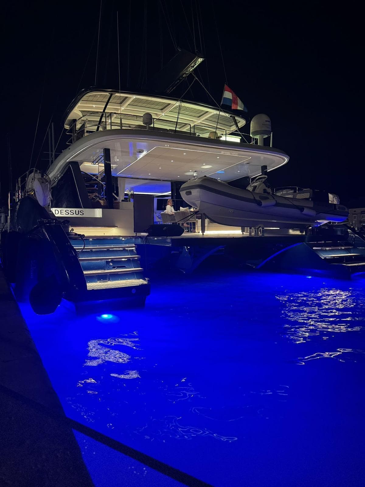 Luxurious 2022 Sunreef 60 yacht illuminated at night with blue underwater lights.