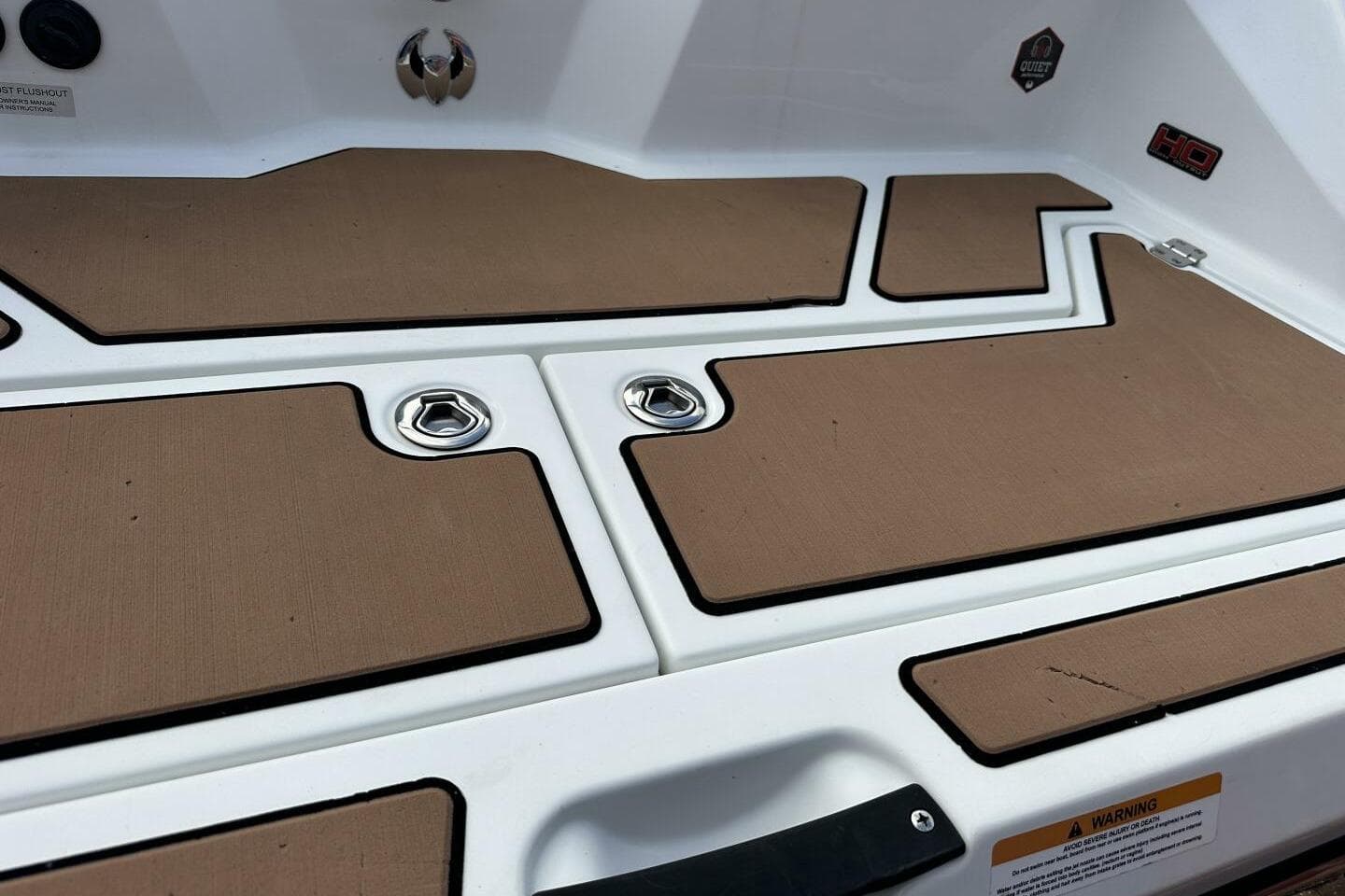 2021 Scarab 215 boat deck with brown non-slip mats and metal fixtures.