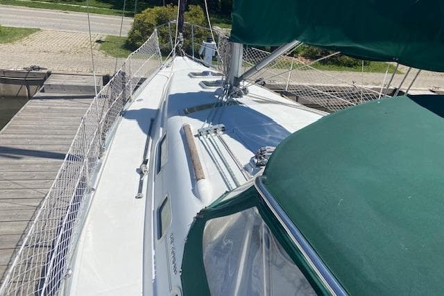 2005 Beneteau 323 sailboat docked, featuring green canopy and sleek deck design.