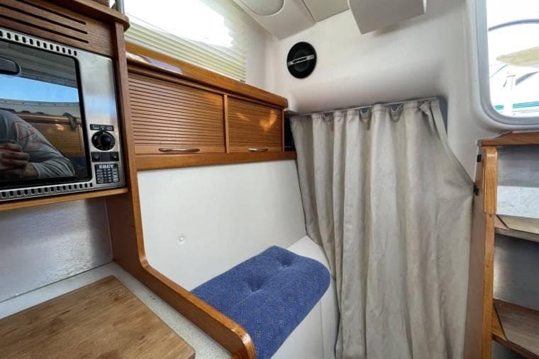 Interior of 2008 Dragonfly 35 Ultimate sailboat with microwave, wooden cabinets, and blue cushioned seat.
