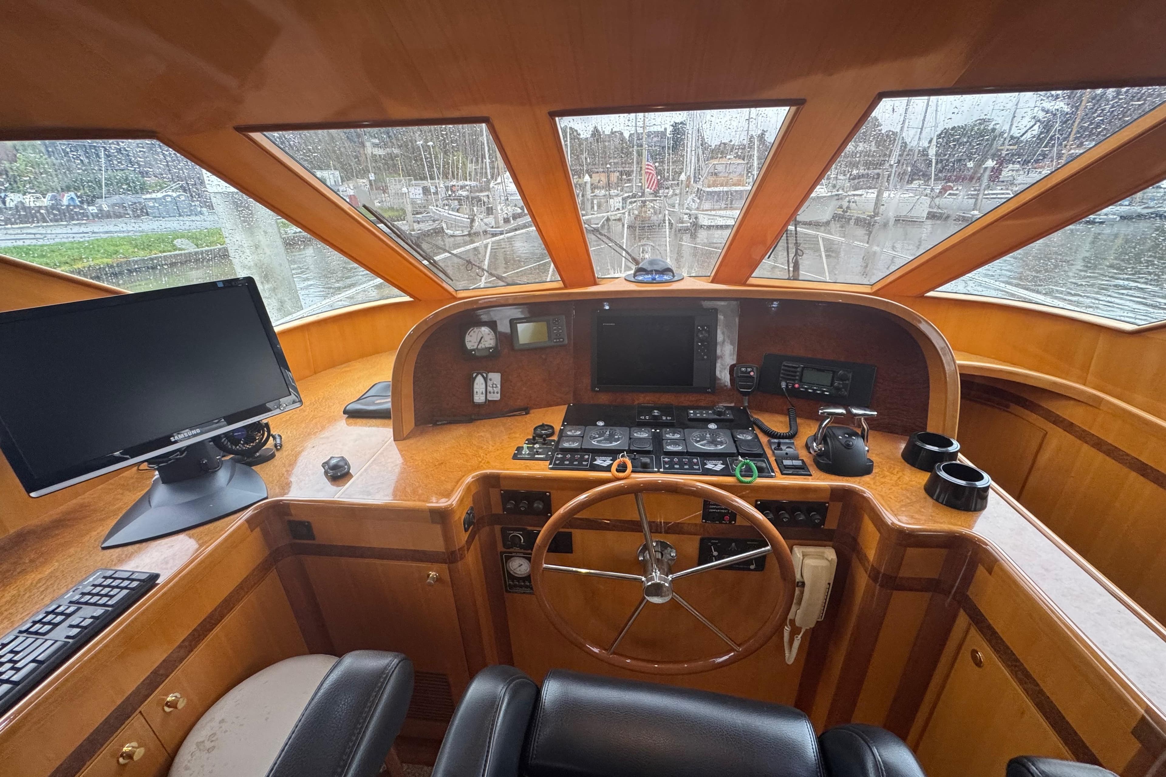 Helm of 2002 Hampton 550 yacht with steering wheel, navigation equipment, and panoramic windows.