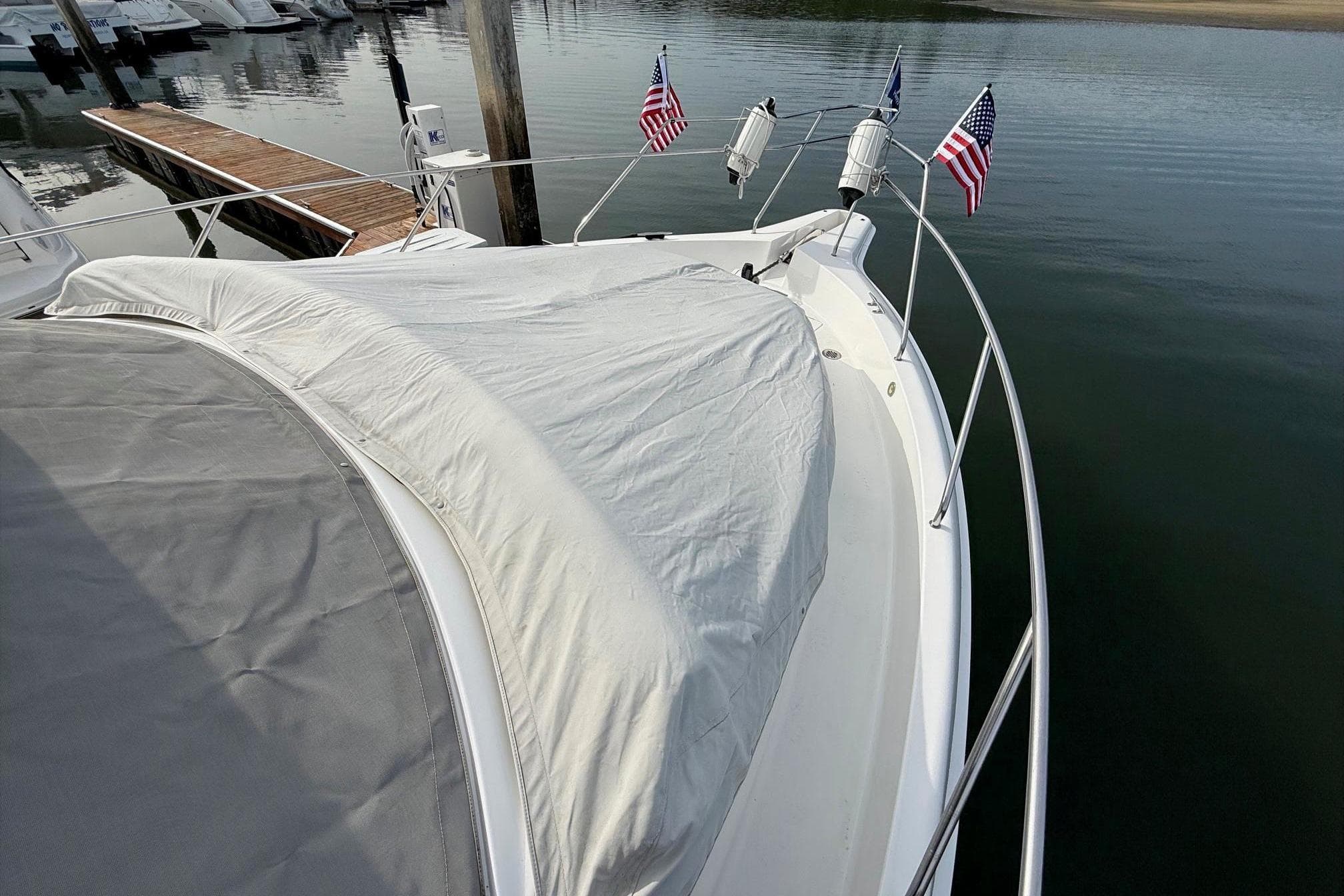1999 Silverton 392 Motor Yacht docked, covered deck, American flags, calm water.