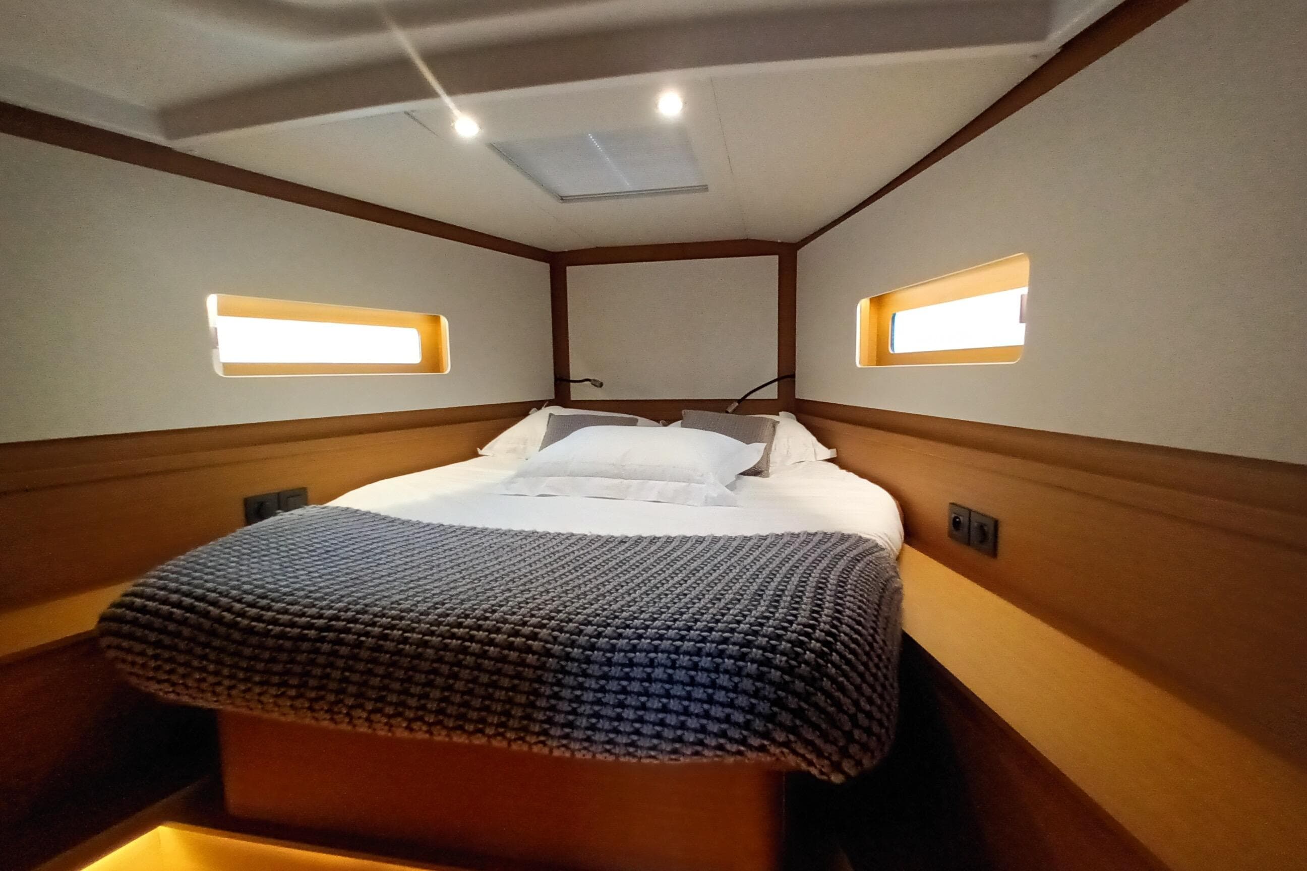 Luxurious cabin interior of 2025 Beneteau First 44 yacht with cozy bedding.