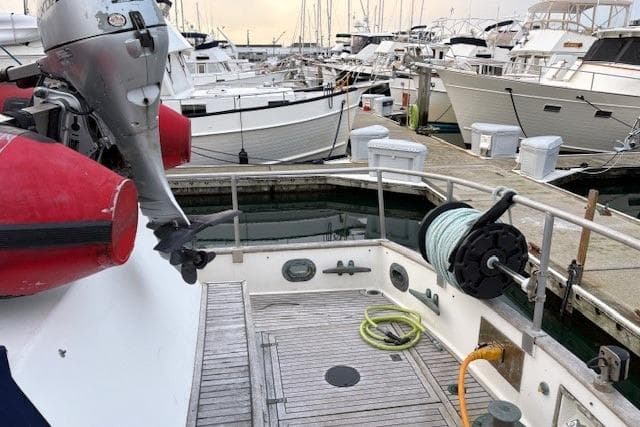 1984 Grand Banks Classic yacht docked at marina with outboard motor and deck equipment.