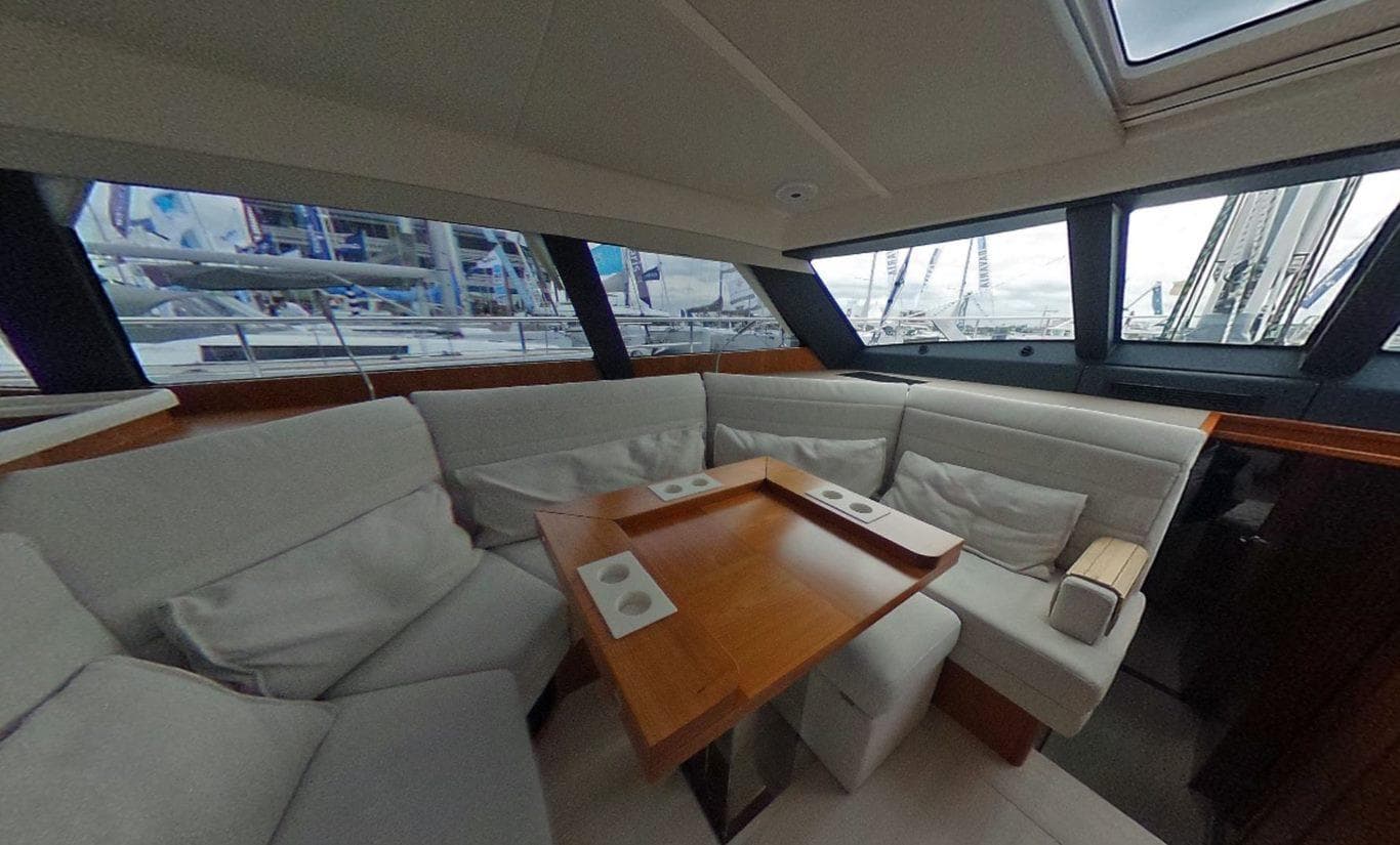 Interior of 2016 Moody 54 DS yacht with plush seating and wooden table.