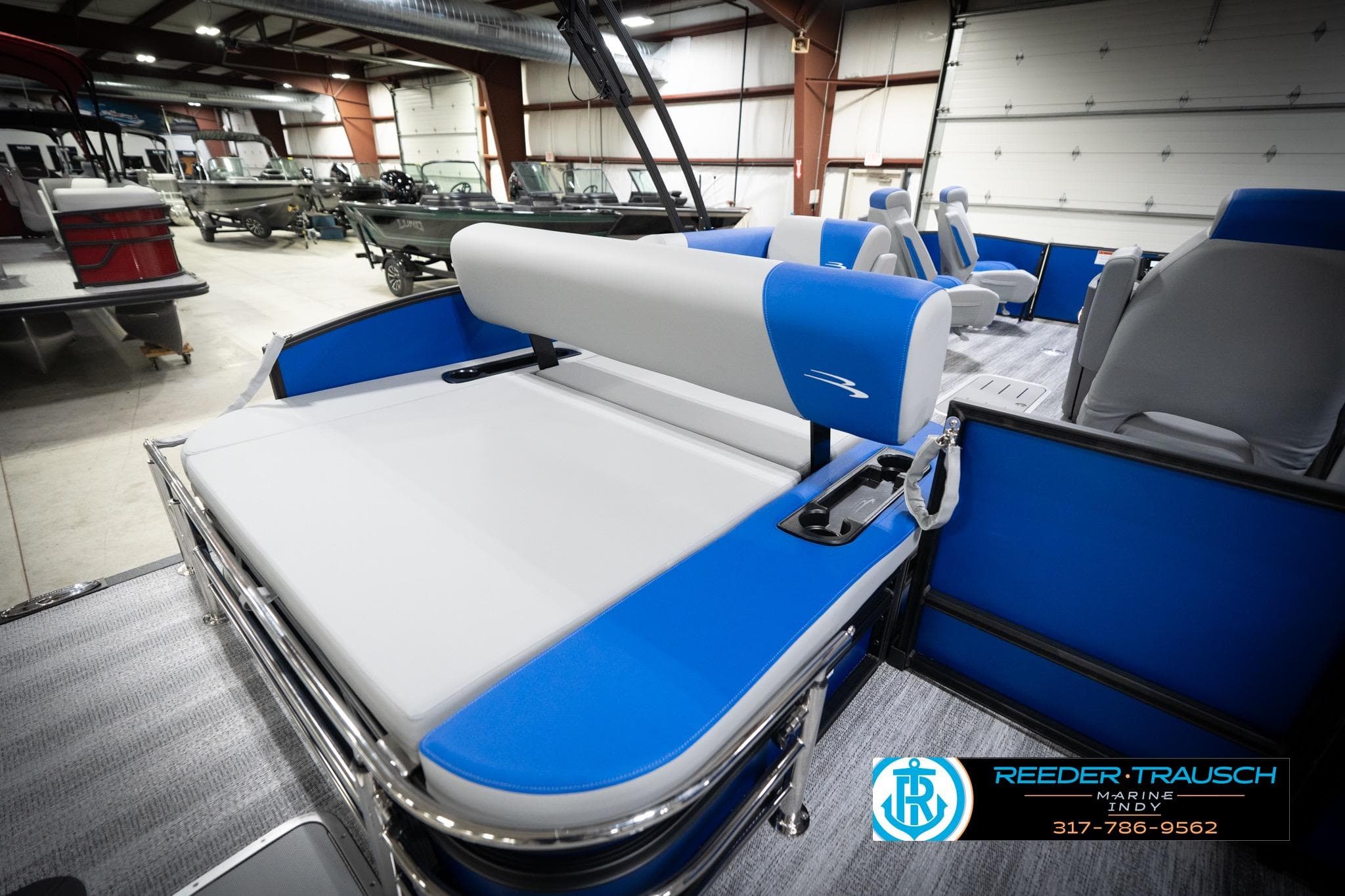 2026 Bennington 22 SSB pontoon boat interior with blue and gray seating in showroom.
