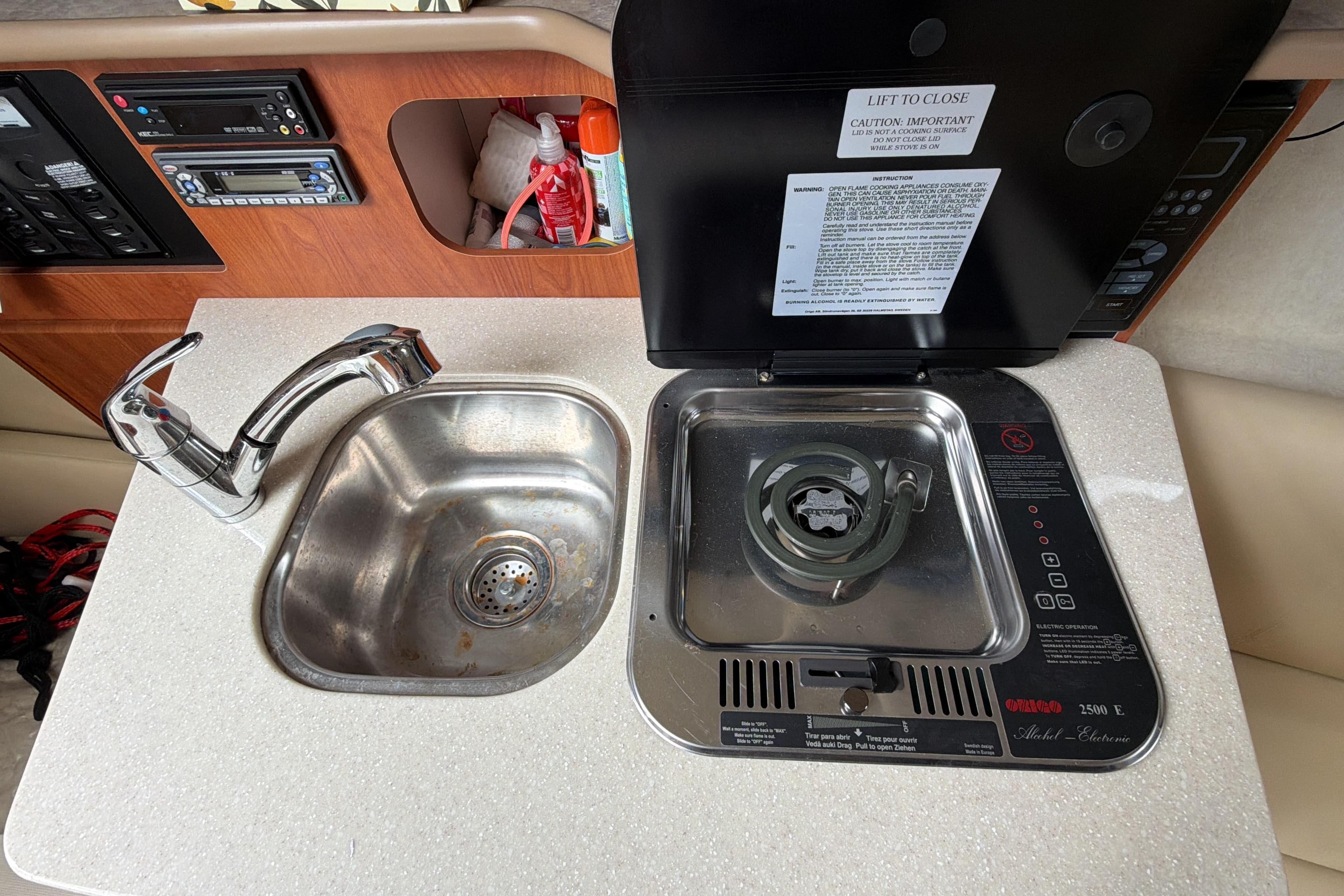 2007 Bayliner 245 boat kitchenette with sink and stove, featuring control panels and storage.