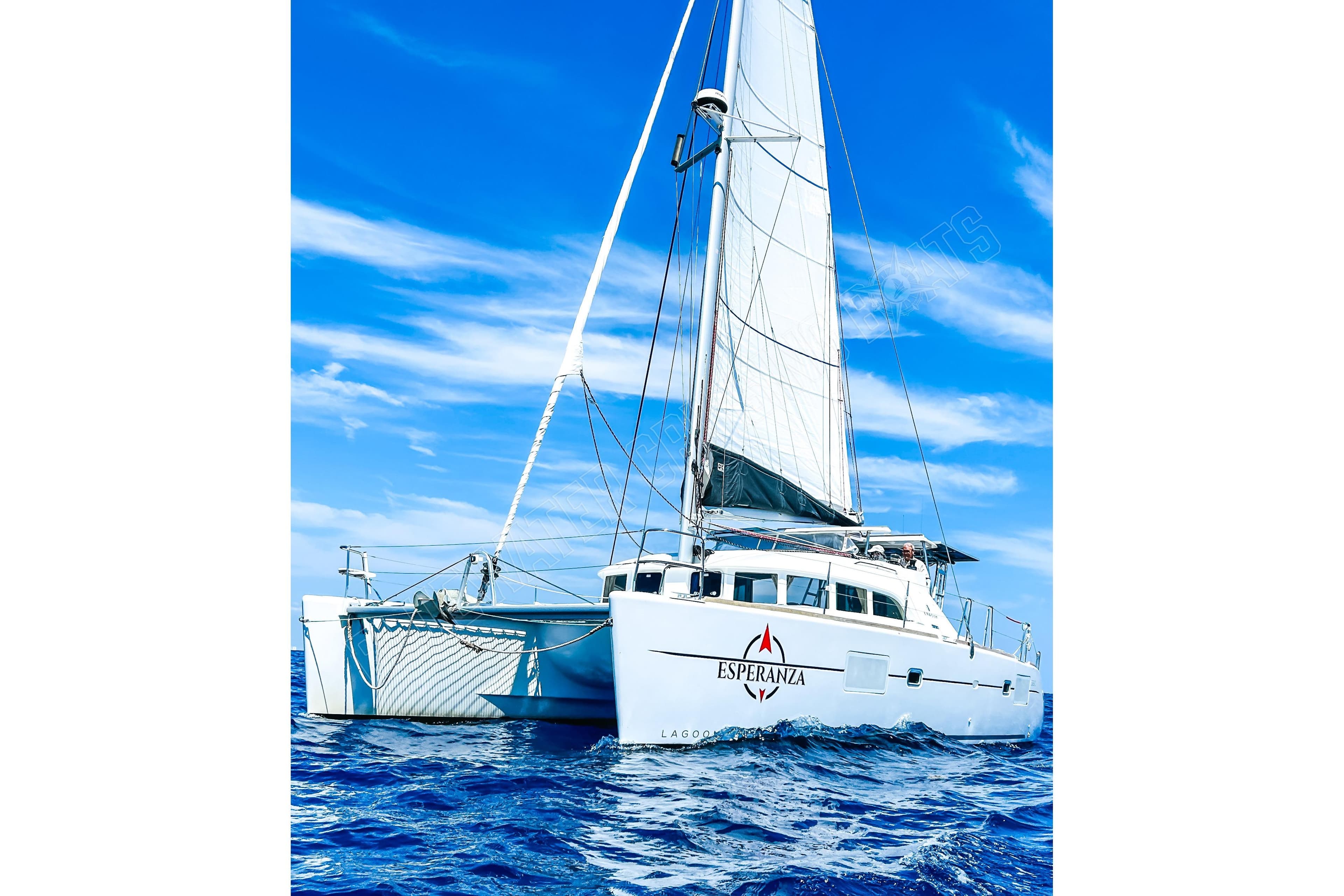 2019 Lagoon 380 S2 catamaran sailing on open sea under clear blue sky.