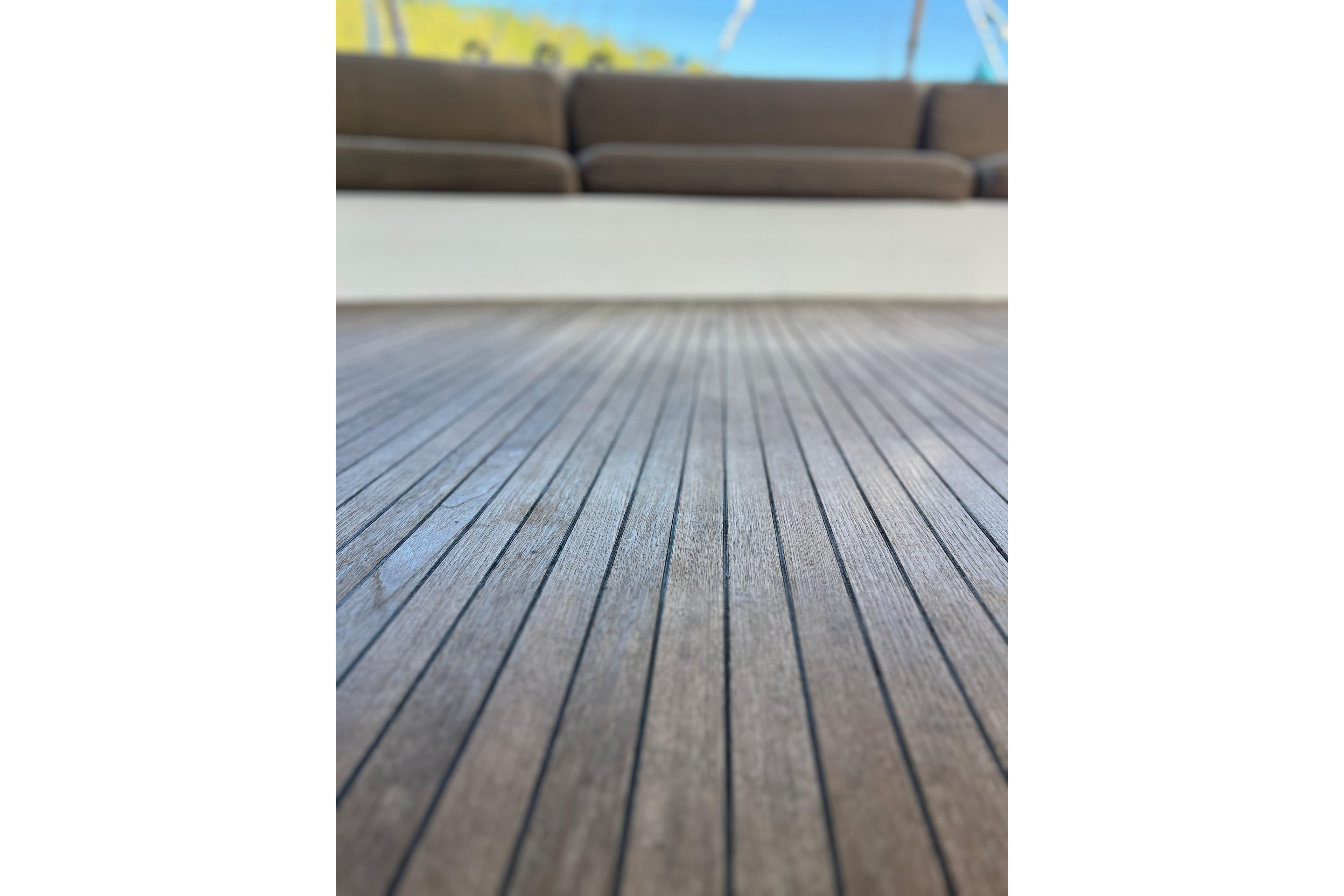 Teak deck of 2005 Concordia Dickson 69 yacht with blurred seating area.