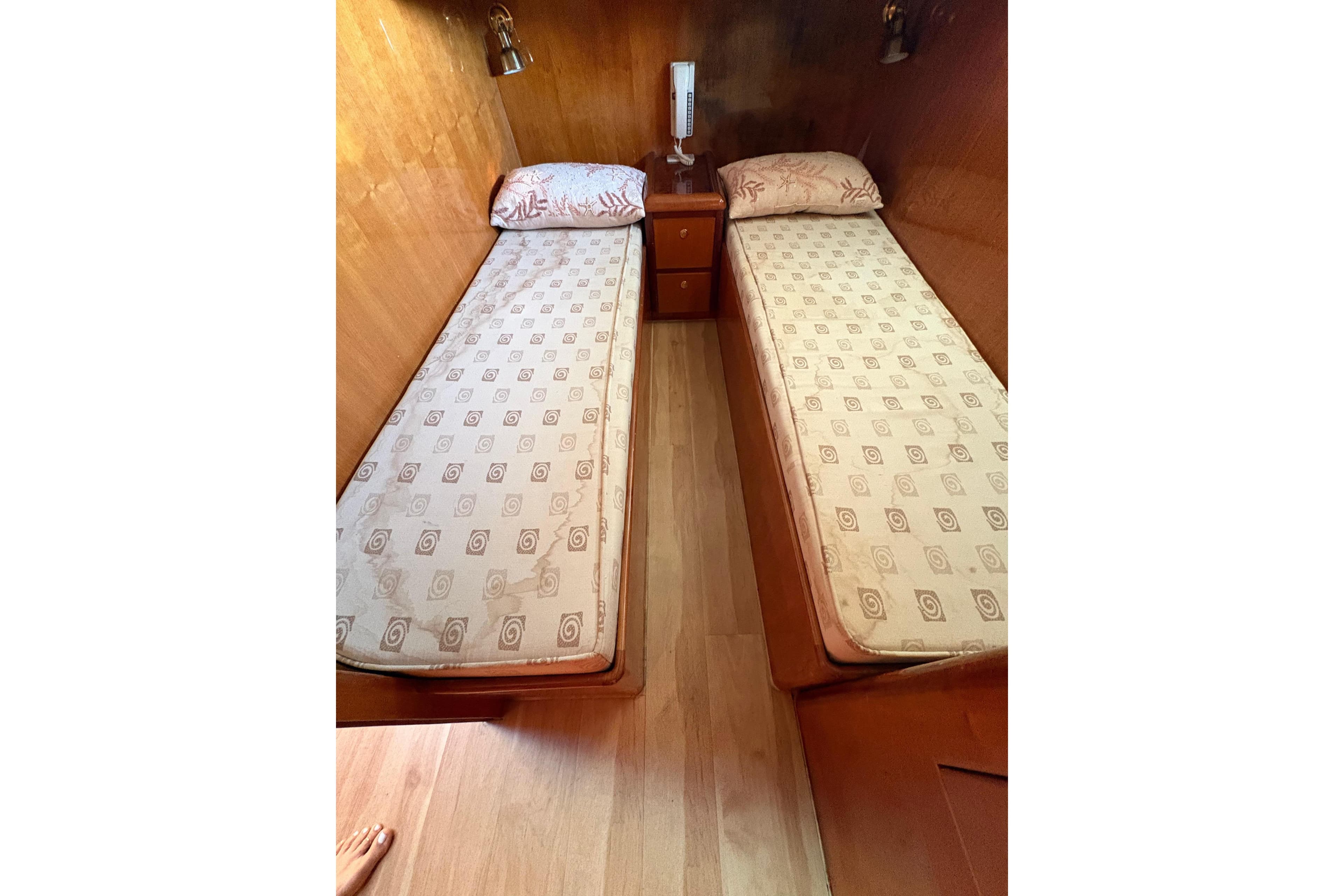 Twin beds in a cozy wooden cabin, featuring patterned mattresses and a central nightstand.